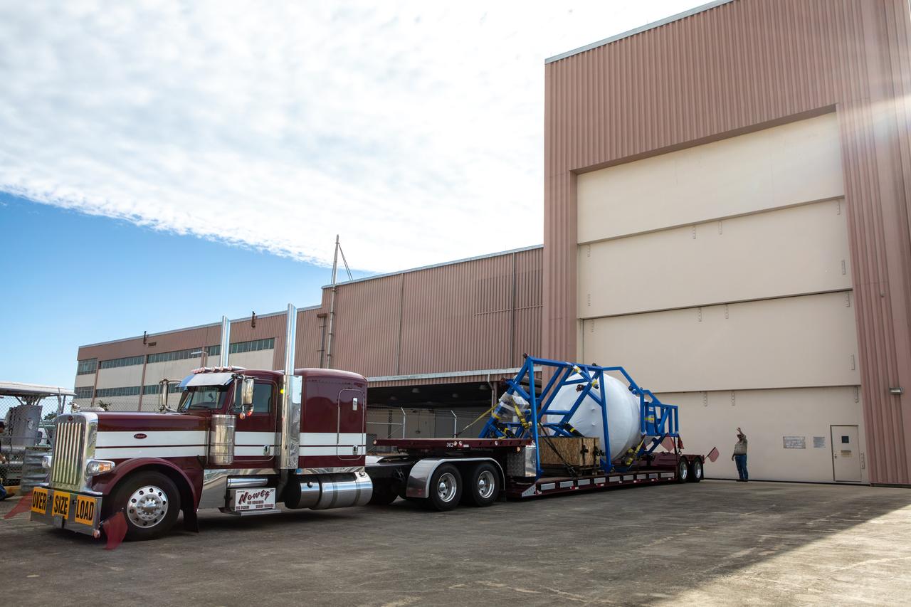 A truck carrying the cargo logistics module for Sierra Nevada Corporation’s Dream Chaser, the company’s reusable spaceplane, arrives at the Space Station Processing Facility high bay entrance at NASA’s Kennedy Space Center in Florida on Aug. 27, 2019. The cargo module – a 15-foot attachment to Dream Chaser – provides extra storage for payloads and provides cargo disposal upon re-entry into Earth’s atmosphere. Dream Chaser will deliver more than 12,000 pounds of cargo to the International Space Station under the agency’s Commercial Resupply Services 2 contract. The spacecraft and cargo module will begin resupply and return services missions to the space station in late 2021. 