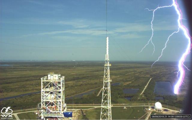A lightning strike is recorded at Launch Complex 39B at NASA’s Kennedy Space Center in Florida in August 2019. The event was captured by high-speed cameras stationed at the pad and mobile launcher using a special filter called a “clear day frame,” which provides an overlay of the raw frame on a reference image. At pad 39B, there are three, 600-foot-tall masts with overhead wires used to transmit electrical energy around the perimeter of the pad to provide lightning protection for launch vehicles as they are processed and launched from the pad.