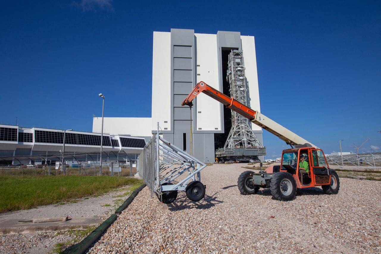 The crawlerway gate is opened as the mobile launcher for NASA’s Artemis missions rolls out of the Vehicle Assembly Building (VAB) at Kennedy Space Center in Florida on Sept. 10, 2019, after spending a week and a half inside due to the approach of Hurricane Dorian. The nearly 400-foot-tall structure was moved from Launch Pad 39B to the VAB for safekeeping on Aug. 30. The storm passed about 70 miles east of the spaceport during the overnight hours Tuesday, Sept. 3, and Wednesday, Sept. 4. NASA’s Exploration Ground Systems is moving the mobile launcher back to the launch pad, where teams will complete testing and checkout on the launcher in the coming weeks for the Artemis I mission.