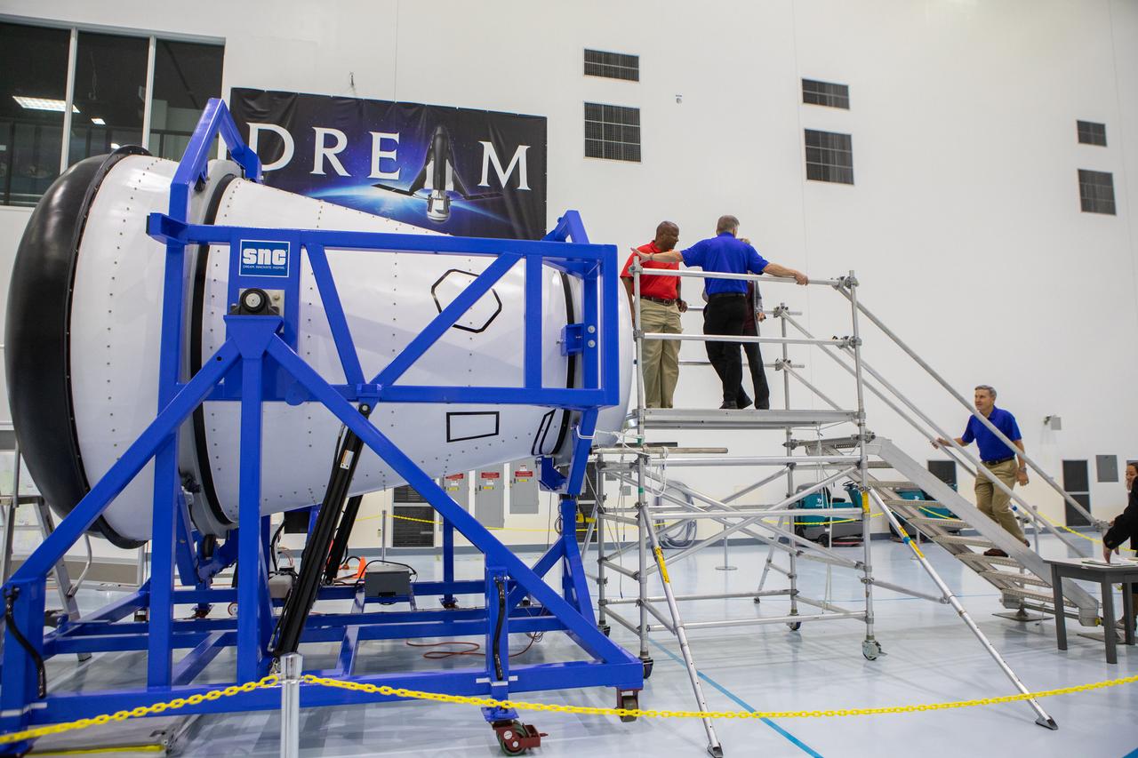 A mockup of the cargo logistics module for Sierra Nevada Corporation’s Dream Chaser, the company’s reusable spaceplane, arrived at the Space Station Processing Facility (SSPF) at NASA’s Kennedy Space Center in Florida in August. On Sept. 20, 2019, senior leadership had the opportunity to view the cargo module in the SSPF high bay. From left are Kelvin Manning, Kennedy associate director, technical; Steve Lindsey, vice president, Space Exploration Systems, Sierra Nevada Corporation; behind Lindsey is Kennedy Deputy Director Janet Petro; and ascending the stairs is Kennedy Center Director Bob Cabana. The SSPF is providing support for current and future NASA and commercial provider programs, including Commercial Resupply Services, Artemis 1, sending the first woman and next man to the Moon, and deep space destinations including Mars.