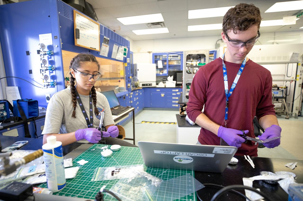 From left, interns Isabella Aviles and Patrick Follis at NASA’s Kennedy Space Center in Florida cut up different types of material for the agency’s Orbital Syngas Commodity Augmentation Reactor, or OSCAR, to use as a trash simulant during microgravity testing. OSCAR is an Early Career Initiative project at the spaceport that studies technology to convert trash and human waste into useful gasses such as methane, hydrogen and carbon dioxide. By processing small pieces of trash in a high-temperature reactor, OSCAR is advancing new and innovative technology for managing waste in space. OSCAR would reduce the amount of space needed for waste storage within a spacecraft, turn some waste into gasses that have energy storage and life support applications, recover water from trash and ensure waste is no longer biologically active. A prototype has been developed, and a team of Kennedy employees are in the process of constructing a new rig for suborbital flight testing. 