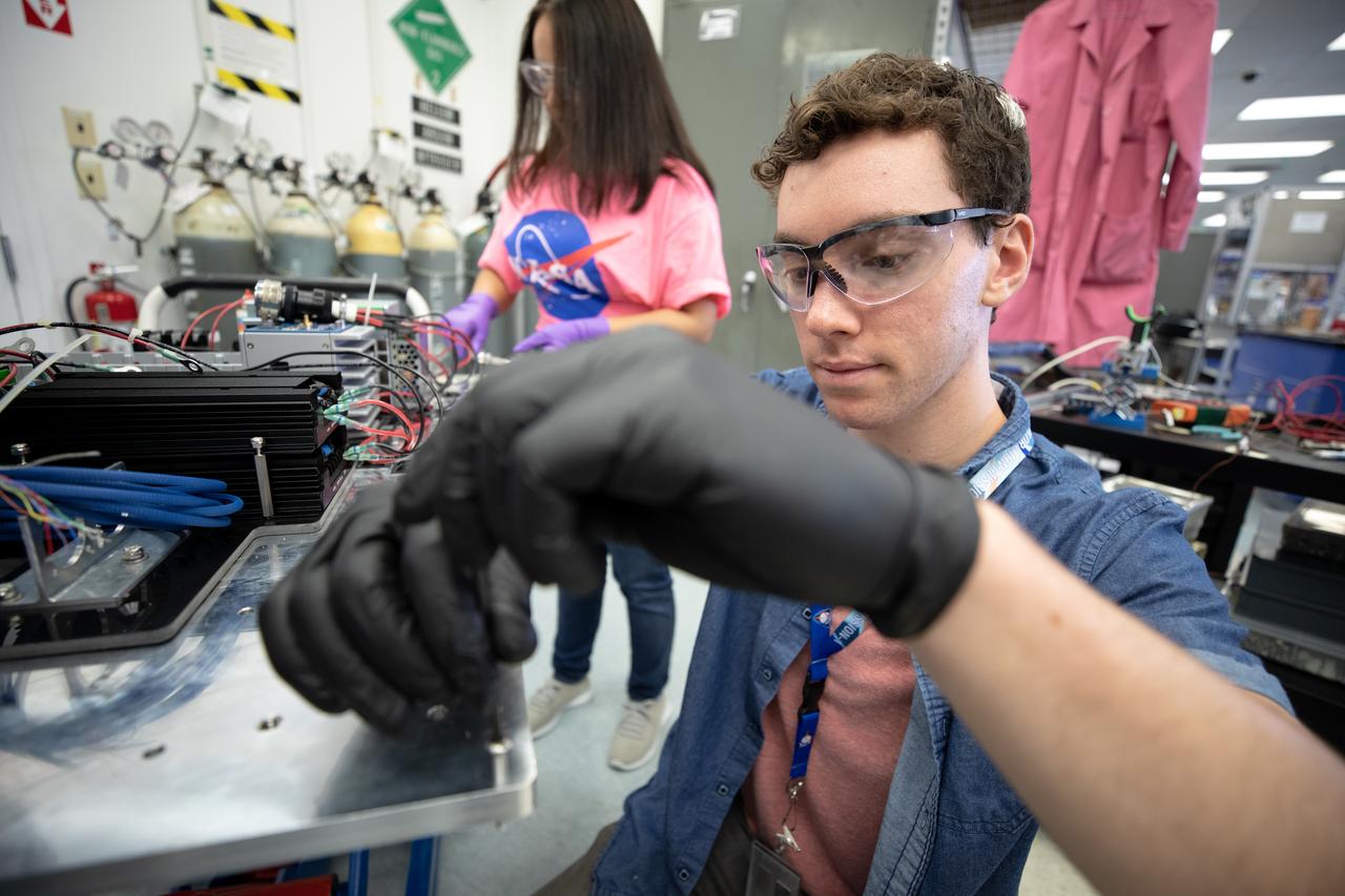 Interns Brianna Sandoval (left) and Patrick Follis at NASA’s Kennedy Space Center in Florida assemble the flight hardware for the agency’s Orbital Syngas Commodity Augmentation Reactor, or OSCAR. OSCAR is an Early Career Initiative project at the spaceport that studies technology to convert trash and human waste into useful gasses such as methane, hydrogen and carbon dioxide. By processing small pieces of trash in a high-temperature reactor, OSCAR is advancing new and innovative technology for managing waste in space. OSCAR would reduce the amount of space needed for waste storage within a spacecraft, turn some waste into gasses that have energy storage and life support applications, and ensure waste is no longer biologically active. A prototype has been developed, and a team of Kennedy employees are in the process of constructing a new rig for suborbital flight testing. 