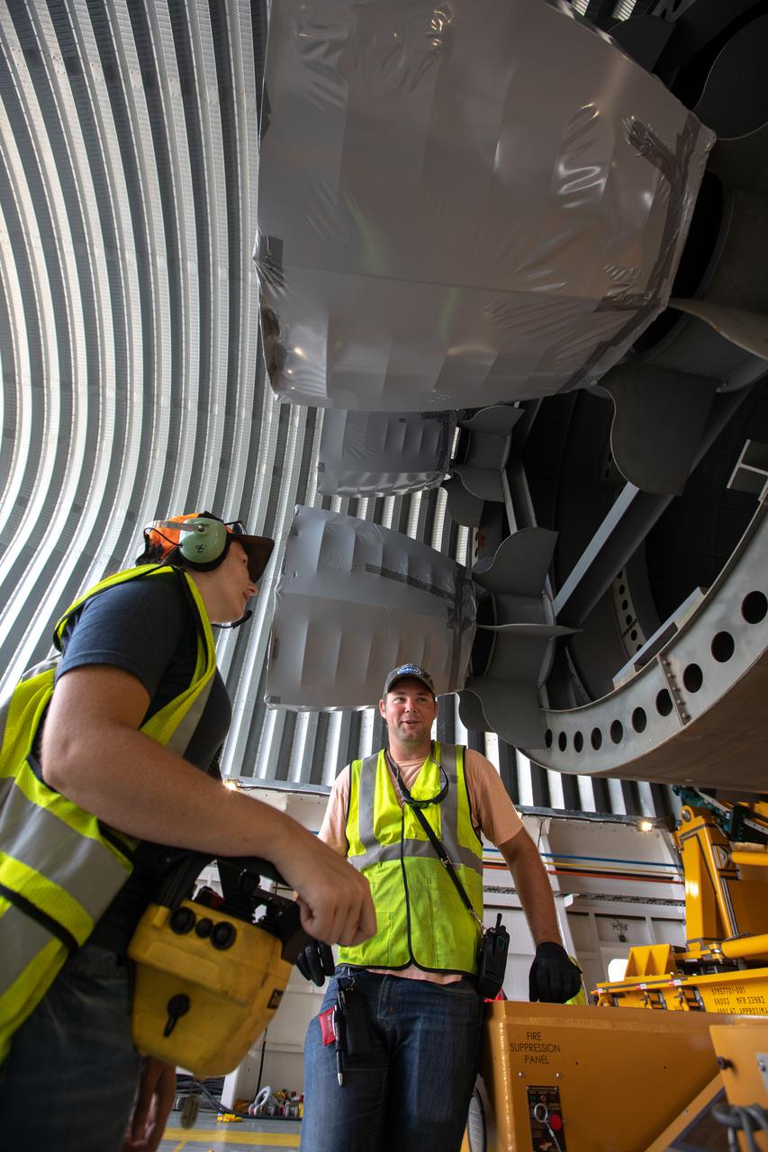 Preparations are underway to offload the 212-foot-long Space Launch System (SLS) rocket core stage pathfinder from NASA's Pegasus Barge at Kennedy Space Center’s Launch Complex 39 turn basin wharf on Oct. 1, 2019. From left, are Katherine River, operator, and James Erdman, observer, both are Launch Vehicle Technical Operations technicians with Jacobs TOSC. The Pegasus Barge made its first delivery to Kennedy in support of the agency's Artemis missions. The upgraded 310-foot-long barge arrived Sept. 27, 2019, ferrying the SLS core stage pathfinder, a full-scale mock-up of the rocket's core stage. It will be used by Exploration Ground Systems and its contractor, Jacobs, to practice offloading, moving and stacking maneuvers, using important ground support equipment to train employees and certify all the equipment works properly. The pathfinder will stay at Kennedy for approximately one month before trekking back to NASA's Michoud Assembly Facility in Louisiana.