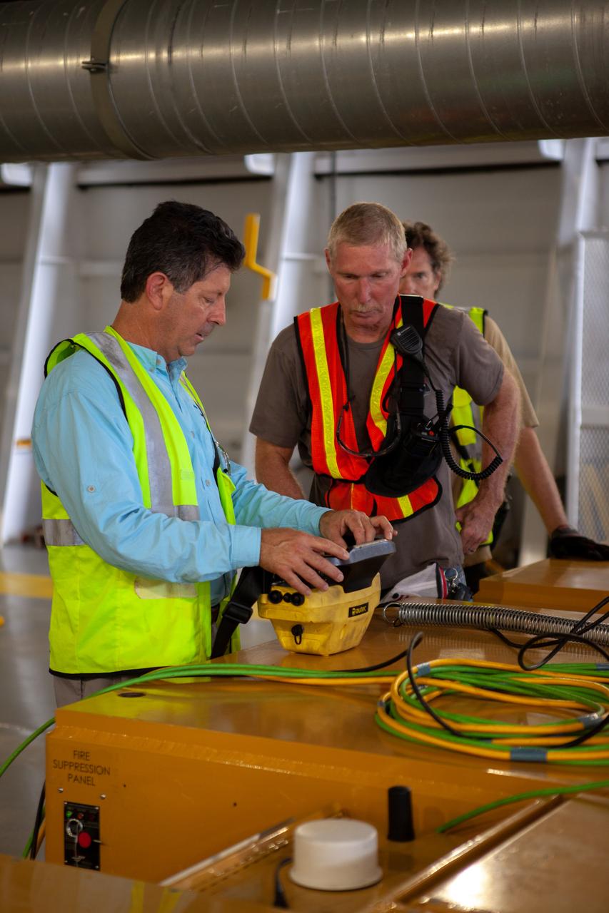 Jacobs TOSC Launch Vehicle Technical Operations technicians review procedures before the start of offloading the 212-foot-long Space Launch System (SLS) rocket core stage pathfinder from NASA's Pegasus Barge at Kennedy Space Center’s Launch Complex 39 turn basin wharf on Oct. 1, 2019. From left, are Dave Goetz, operator, John Stirling and Jack Gardner, both observers. The Pegasus Barge made its first delivery to Kennedy in support of the agency's Artemis missions. The upgraded 310-foot-long barge arrived Sept. 27, 2019, ferrying the SLS core stage pathfinder, a full-scale mock-up of the rocket's core stage. It will be used by Exploration Ground Systems and its contractor, Jacobs, to practice offloading, moving and stacking maneuvers, using important ground support equipment to train employees and certify all the equipment works properly. The pathfinder will stay at Kennedy for approximately one month before trekking back to NASA's Michoud Assembly Facility in Louisiana.