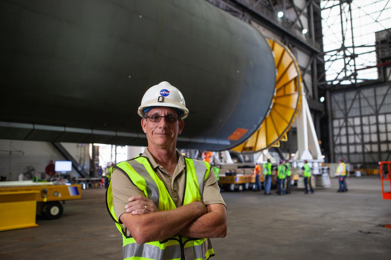 Jim Bolton, Core Stage Element Operations manager in Exploration Ground Systems (EGS), is at the north end of the transfer aisle in the Vehicle Assembly Building at NASA’s Kennedy Space Center in Florida on Oct. 3, 2019. Behind him is the Space Launch System Core Stage pathfinder. A cover, called a spider, is being attached to the top of the pathfinder. With the spider secured in place, a crane will be attached to it to lift the pathfinder into the vertical position. The 212-foot-long core stage pathfinder arrived aboard NASA's Pegasus Barge at Kennedy’s Launch Complex 39 turn basin wharf on Sept. 27, 2019. The Pegasus Barge made its first delivery to Kennedy in support of the agency's Artemis missions. The upgraded 310-foot-long barge arrived, ferrying the SLS core stage pathfinder, a full-scale mock-up of the rocket's core stage. It will be used by EGS and its contractor, Jacobs, to practice offloading, moving and stacking maneuvers, using important ground support equipment to train employees and certify all the equipment works properly. The pathfinder will stay at Kennedy for approximately one month before trekking back to NASA's Michoud Assembly Facility in Louisiana.