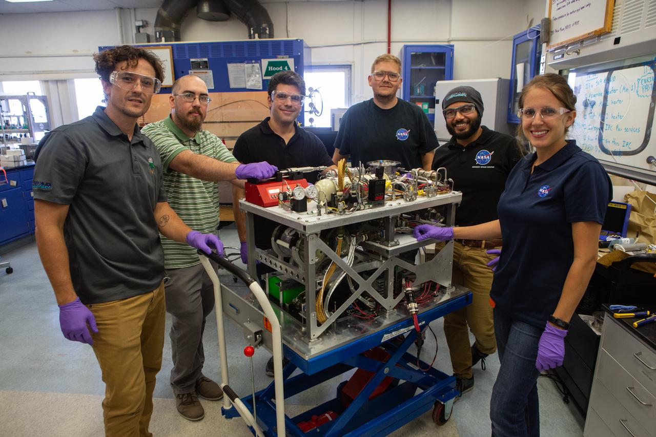 Members of NASA’s Orbital Syngas Commodity Augmentation Reactor, or OSCAR, team pause for a photo with the flight hardware on Oct. 10, 2019, in the Space Station Processing Facility at the agency’s Kennedy Space Center in Florida. From left are Gino Carro, Tom Cauvel, Jaime Toro, Evan Bell, Malay Shah and Annie Meier. OSCAR is an Early Career Initiative project at the spaceport that studies technology to convert trash and human waste into useful gasses such as methane, hydrogen and carbon dioxide. By processing small pieces of trash in a high-temperature reactor, OSCAR is advancing new and innovative technology for managing waste in space. A prototype has been developed, and the team is in the process of constructing a new rig for a suborbital flight test.