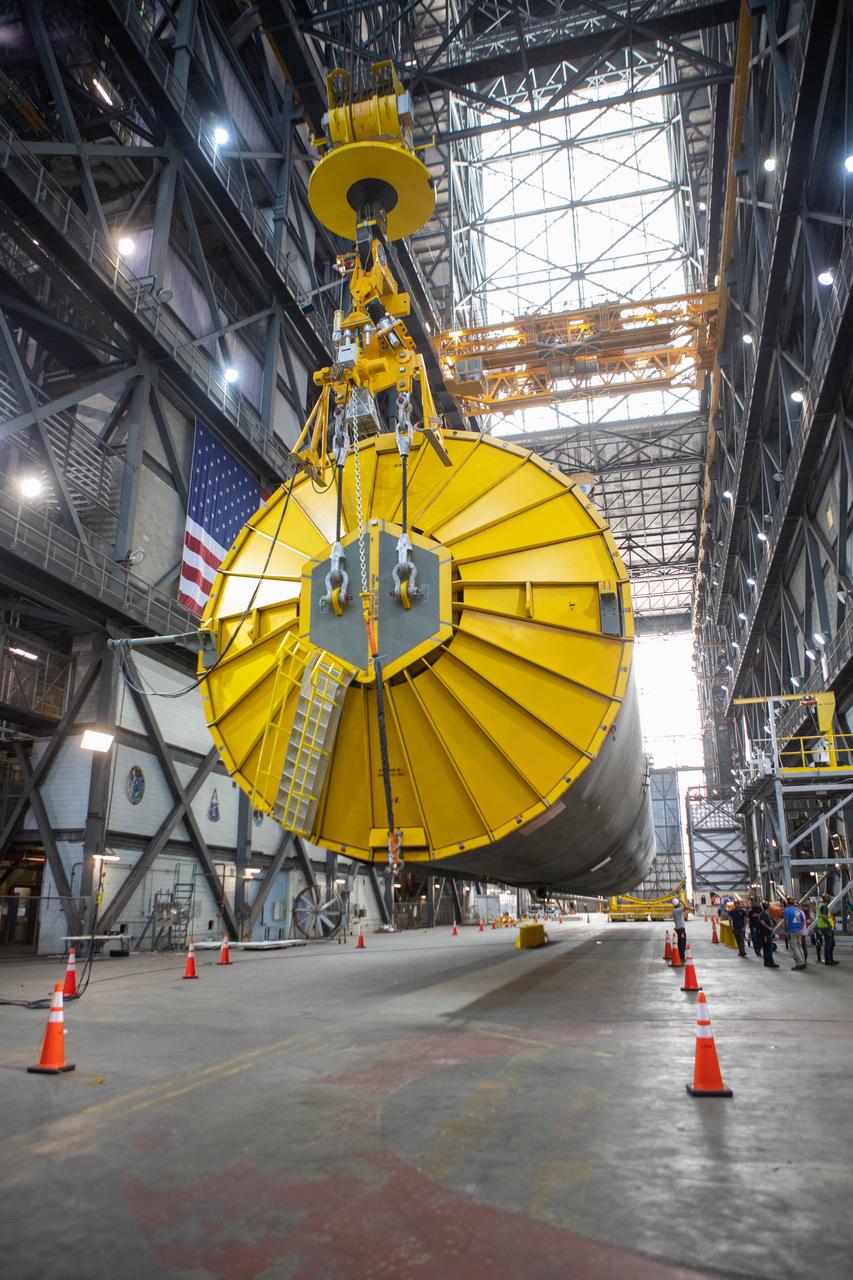 Inside the Vehicle Assembly Building at NASA’s Kennedy Space Center in Florida, two cranes are used to lift the Space Launch System (SLS) Core Stage pathfinder horizontally in the transfer aisle on Oct. 15, 2019. A cover, called the spider, is in view on the top of the pathfinder. A crane is attached to the spider to help lift the pathfinder. The 212-foot-long core stage pathfinder arrived on NASA's Pegasus Barge at Kennedy’s Launch Complex 39 turn basin wharf on Sept. 27, 2019. The Pegasus Barge made its first delivery to Kennedy in support of the agency's Artemis missions. The pathfinder is being used by Exploration Ground Systems and its contractor, Jacobs, to practice offloading, moving and stacking maneuvers, using important ground support equipment to train employees and certify all the equipment works properly. The pathfinder will stay at Kennedy through at least the month of October before trekking back to NASA's Michoud Assembly Facility in Louisiana.