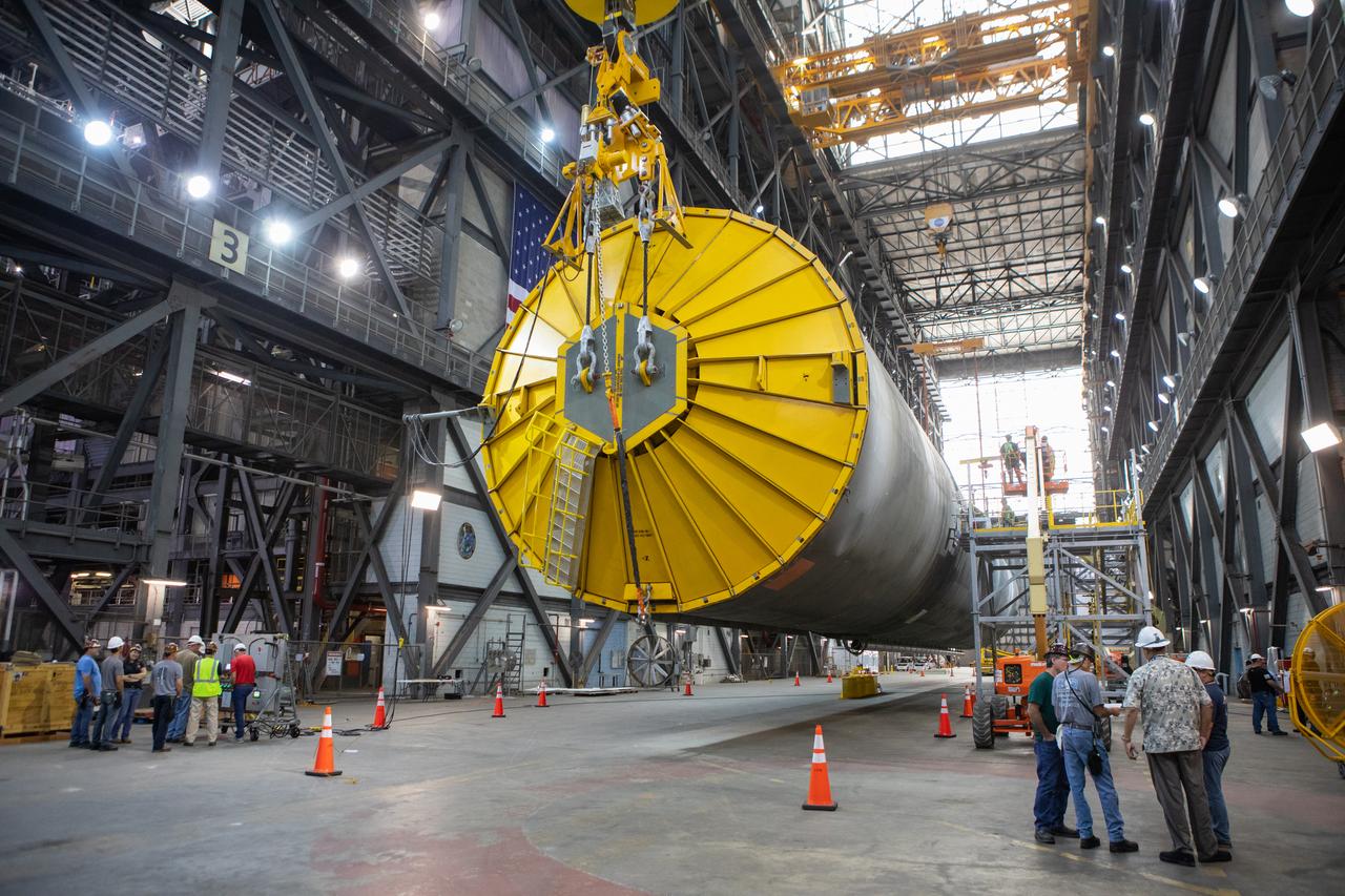Inside the Vehicle Assembly Building at NASA’s Kennedy Space Center in Florida, workers watch the progress as two cranes are used to lift the Space Launch System (SLS) Core Stage pathfinder horizontally in the transfer aisle on Oct. 15, 2019. The 212-foot-long core stage pathfinder arrived on NASA's Pegasus Barge at Kennedy’s Launch Complex 39 turn basin wharf on Sept. 27, 2019. The Pegasus Barge made its first delivery to Kennedy in support of the agency's Artemis missions. The pathfinder is being used by Exploration Ground Systems and its contractor, Jacobs, to practice offloading, moving and stacking maneuvers, using important ground support equipment to train employees and certify all the equipment works properly. The pathfinder will stay at Kennedy through at least the month of October before trekking back to NASA's Michoud Assembly Facility in Louisiana.