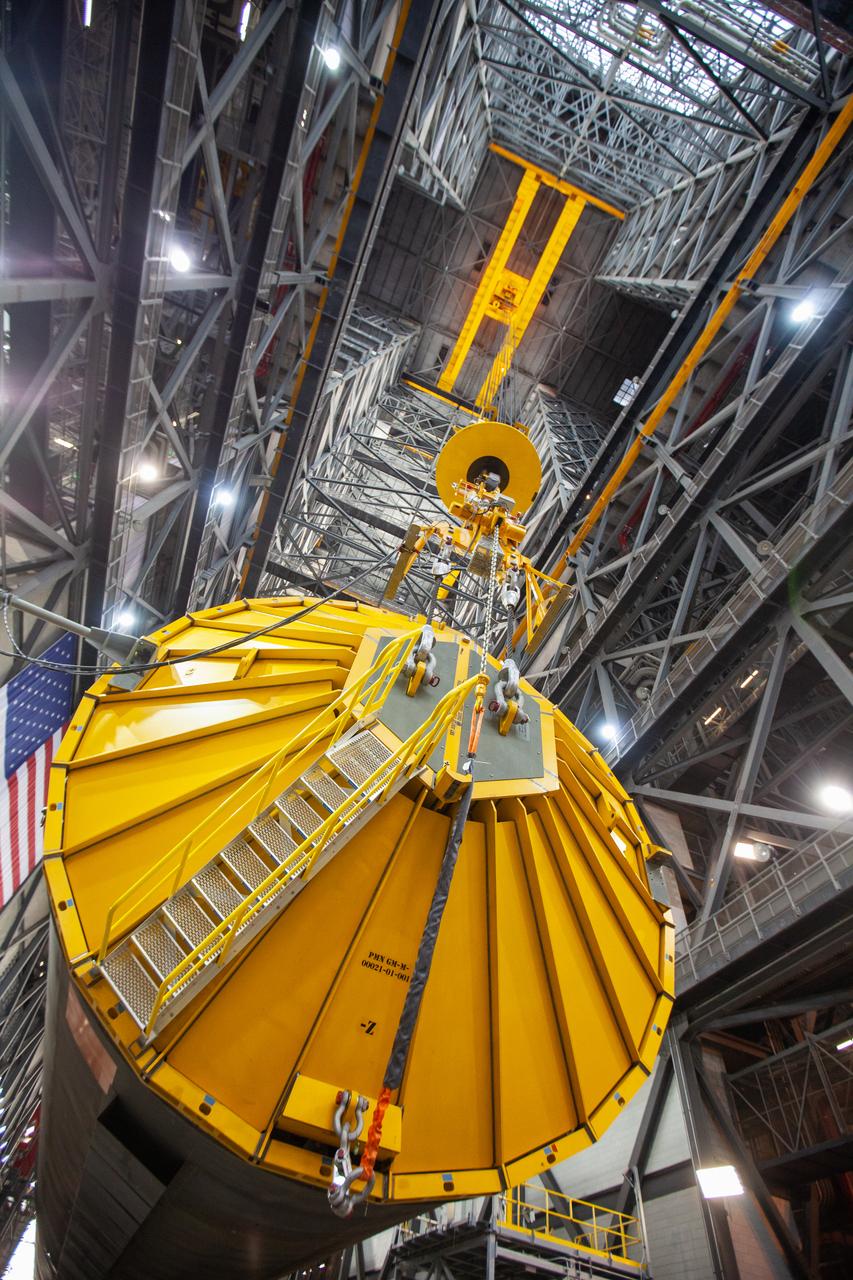 In this close-up view inside the Vehicle Assembly Building at NASA’s Kennedy Space Center in Florida, a special cover called the spider and a crane are in view on top of the Space Launch System (SLS) Core Stage pathfinder as it is being lifted horizontally in the transfer aisle on Oct. 15, 2019. The 212-foot-long core stage pathfinder arrived on NASA's Pegasus Barge at Kennedy’s Launch Complex 39 turn basin wharf on Sept. 27, 2019. The Pegasus Barge made its first delivery to Kennedy in support of the agency's Artemis missions. The pathfinder is being used by Exploration Ground Systems and its contractor, Jacobs, to practice offloading, moving and stacking maneuvers, using important ground support equipment to train employees and certify all the equipment works properly. The pathfinder will stay at Kennedy through at least the month of October before trekking back to NASA's Michoud Assembly Facility in Louisiana.