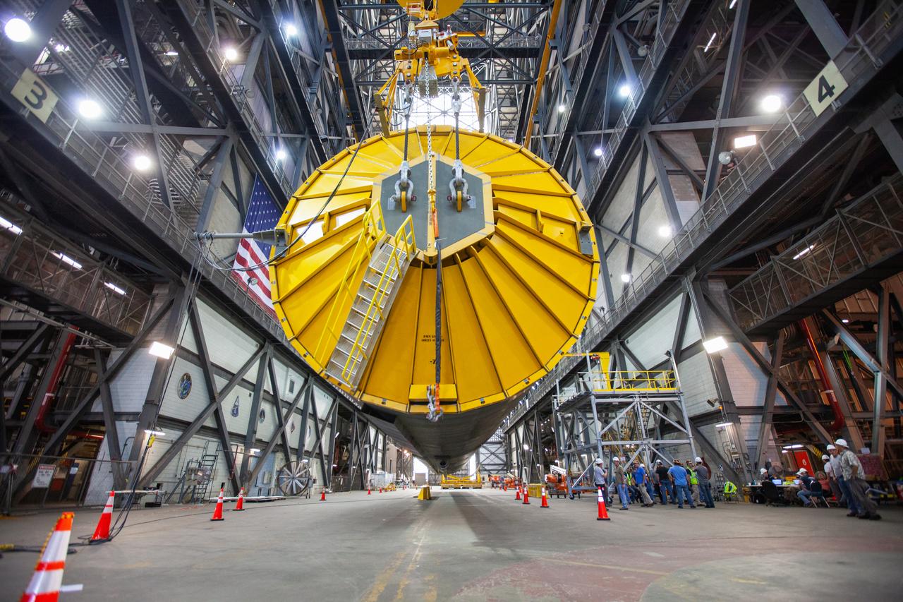In this close-up view inside the Vehicle Assembly Building at NASA’s Kennedy Space Center in Florida, a special cover called the spider and a crane are in view on top of the Space Launch System (SLS) Core Stage pathfinder as it is being lifted horizontally in the transfer aisle on Oct. 15, 2019. The 212-foot-long core stage pathfinder arrived on NASA's Pegasus Barge at Kennedy’s Launch Complex 39 turn basin wharf on Sept. 27, 2019. The Pegasus Barge made its first delivery to Kennedy in support of the agency's Artemis missions. The pathfinder is being used by Exploration Ground Systems and its contractor, Jacobs, to practice offloading, moving and stacking maneuvers, using important ground support equipment to train employees and certify all the equipment works properly. The pathfinder will stay at Kennedy through at least the month of October before trekking back to NASA's Michoud Assembly Facility in Louisiana.