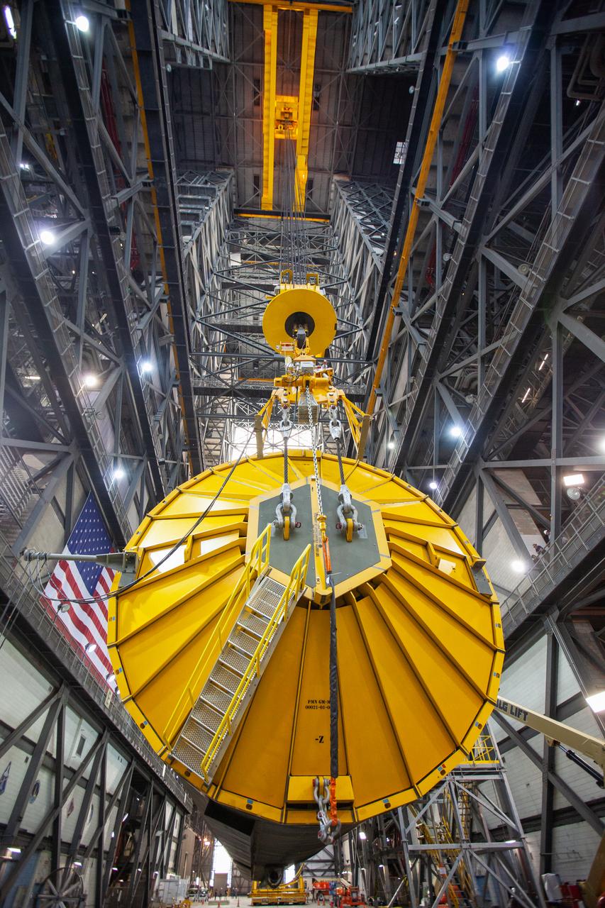 In this close-up view inside the Vehicle Assembly Building at NASA’s Kennedy Space Center in Florida, a special cover called the spider and a crane are in view on top of the Space Launch System (SLS) Core Stage pathfinder as it is being lifted horizontally in the transfer aisle on Oct. 15, 2019. The 212-foot-long core stage pathfinder arrived on NASA's Pegasus Barge at Kennedy’s Launch Complex 39 turn basin wharf on Sept. 27, 2019. The Pegasus Barge made its first delivery to Kennedy in support of the agency's Artemis missions. The pathfinder is being used by Exploration Ground Systems and its contractor, Jacobs, to practice offloading, moving and stacking maneuvers, using important ground support equipment to train employees and certify all the equipment works properly. The pathfinder will stay at Kennedy through at least the month of October before trekking back to NASA's Michoud Assembly Facility in Louisiana.