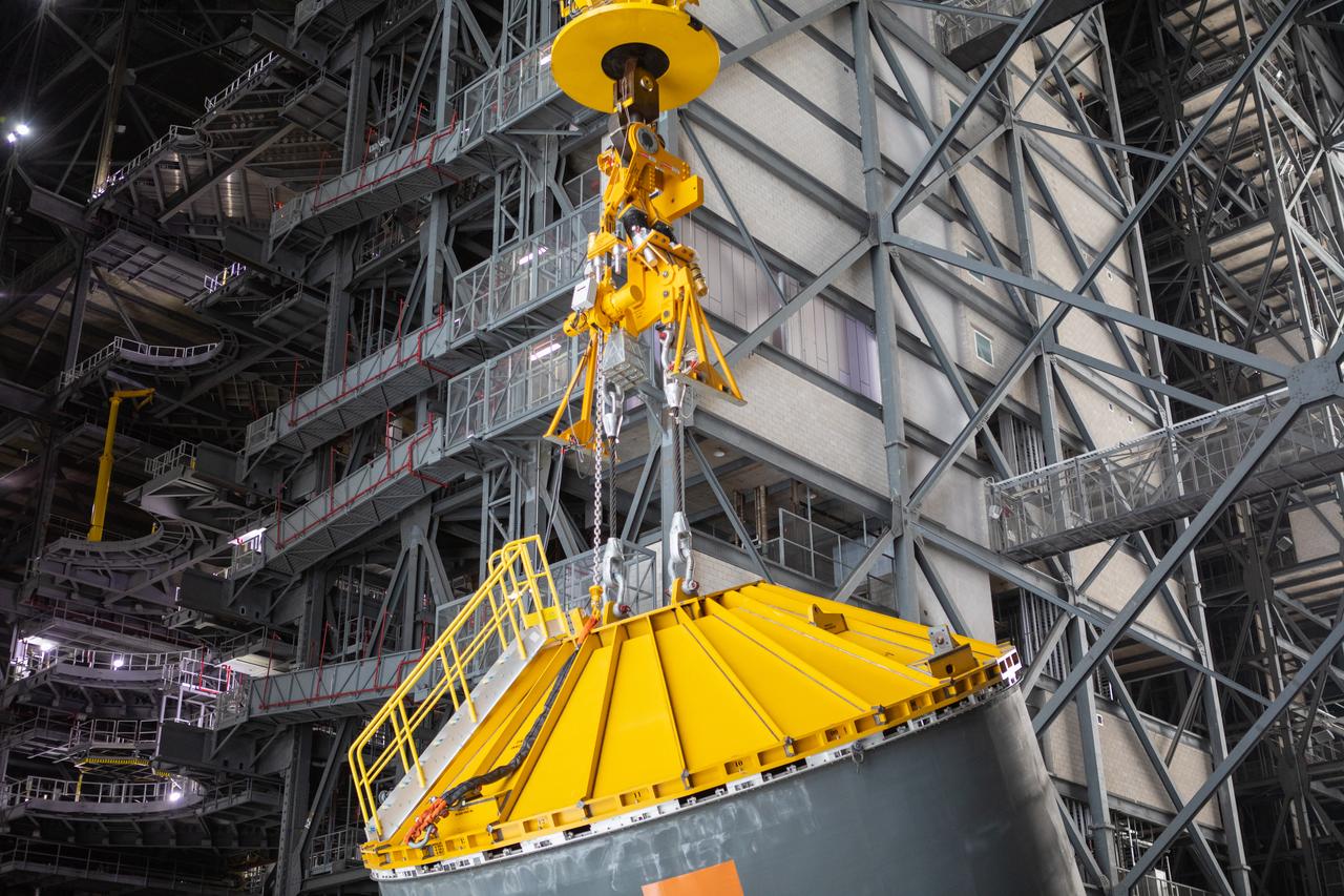 In this close-up view inside the Vehicle Assembly Building at NASA’s Kennedy Space Center in Florida, a crane and special cover, called a spider, attached to the top of the Space Launch System (SLS) Core Stage pathfinder, are used to lift the pathfinder into the vertical position in the transfer aisle on Oct. 15, 2019. The 212-foot-long core stage pathfinder arrived on NASA's Pegasus Barge at Kennedy’s Launch Complex 39 turn basin wharf on Sept. 27, 2019. The Pegasus Barge made its first delivery to Kennedy in support of the agency's Artemis missions. The pathfinder is being used by Exploration Ground Systems and its contractor, Jacobs, to practice offloading, moving and stacking maneuvers, using important ground support equipment to train employees and certify all the equipment works properly. The pathfinder will stay at Kennedy through at least the month of October before trekking back to NASA's Michoud Assembly Facility in Louisiana.