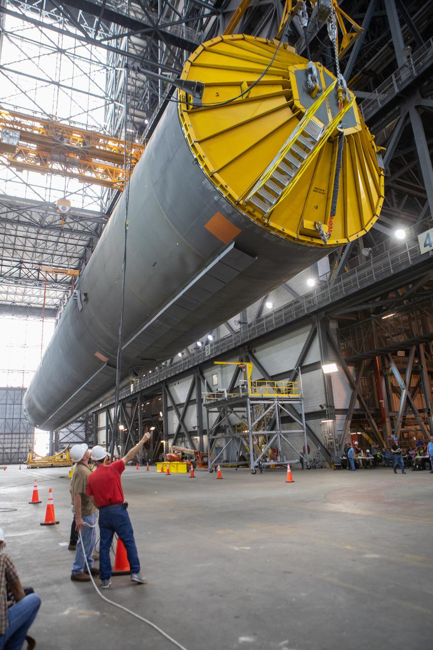 Inside the Vehicle Assembly Building at NASA’s Kennedy Space Center in Florida, workers assist as the Space Launch System (SLS) Core Stage pathfinder is suspended by two cranes in the horizontal position above the transfer aisle on Oct. 15, 2019. The 212-foot-long core stage pathfinder arrived on NASA's Pegasus Barge at Kennedy’s Launch Complex 39 turn basin wharf on Sept. 27, 2019. The Pegasus Barge made its first delivery to Kennedy in support of the agency's Artemis missions. The pathfinder is being used by Exploration Ground Systems and its contractor, Jacobs, to practice offloading, moving and stacking maneuvers, using important ground support equipment to train employees and certify all the equipment works properly. The pathfinder will stay at Kennedy through at least the month of October before trekking back to NASA's Michoud Assembly Facility in Louisiana.