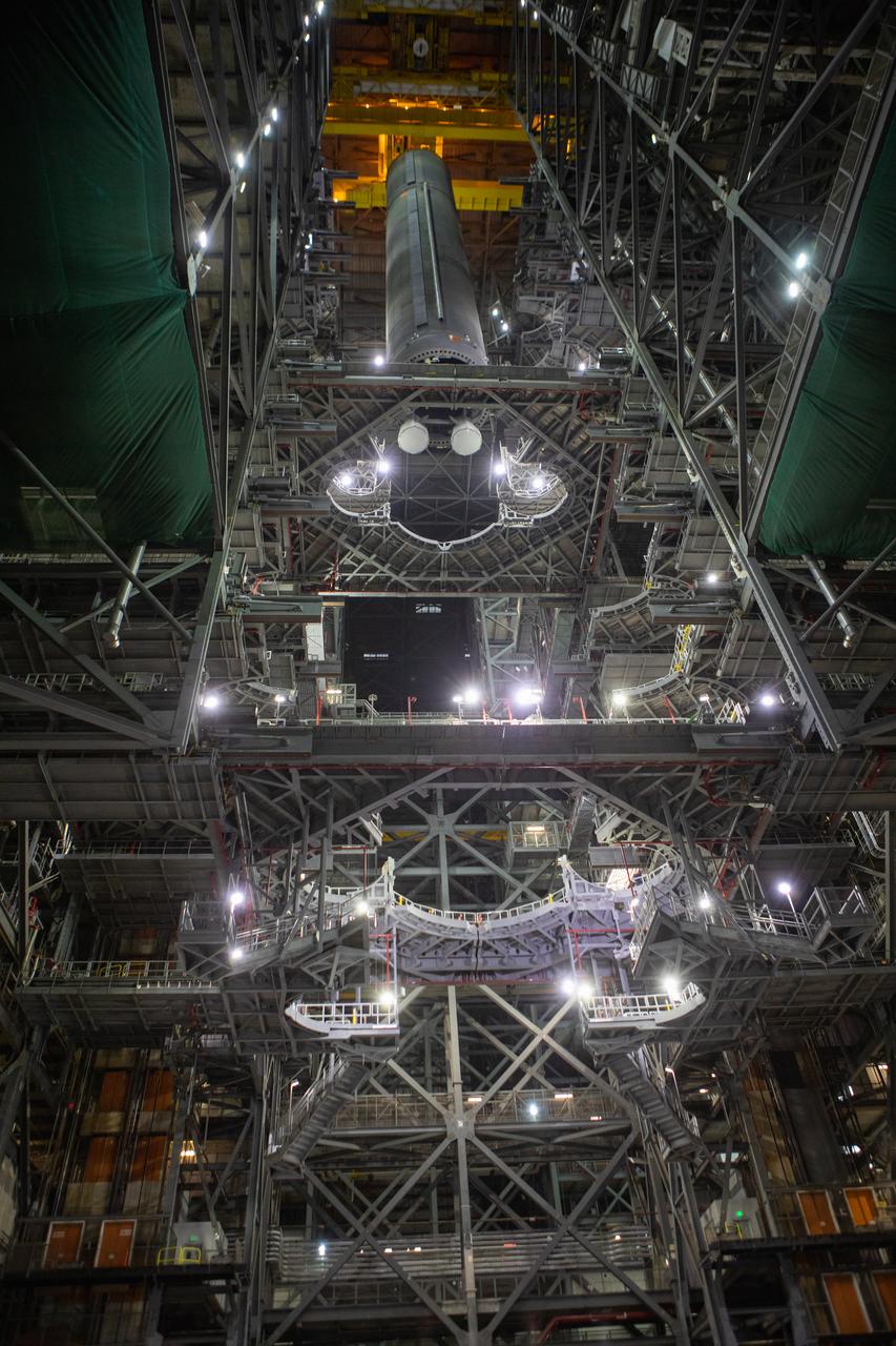 In this view looking up inside the Vehicle Assembly Building at NASA’s Kennedy Space Center in Florida, a crane lowers the Space Launch System (SLS) Core Stage pathfinder into High Bay 3 on Oct. 16, 2019. The 212-foot-long core stage pathfinder arrived on NASA's Pegasus Barge at Kennedy’s Launch Complex 39 turn basin wharf on Sept. 27, 2019. The Pegasus Barge made its first delivery to Kennedy in support of the agency's Artemis missions. The pathfinder is being used by Exploration Ground Systems and its contractor, Jacobs, to practice offloading, moving and stacking maneuvers, using important ground support equipment to train employees and certify all the equipment works properly. The pathfinder will stay at Kennedy through at least the month of October before trekking back to NASA's Michoud Assembly Facility in Louisiana.