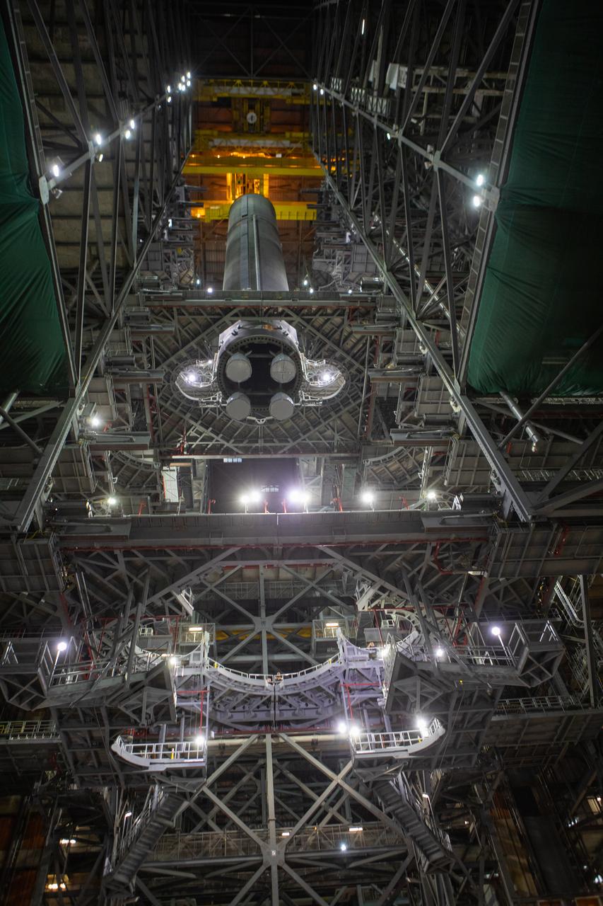 In this view looking up inside the Vehicle Assembly Building at NASA’s Kennedy Space Center in Florida, a crane lowers the Space Launch System (SLS) Core Stage pathfinder into High Bay 3 on Oct. 16, 2019. The 212-foot-long core stage pathfinder arrived on NASA's Pegasus Barge at Kennedy’s Launch Complex 39 turn basin wharf on Sept. 27, 2019. The Pegasus Barge made its first delivery to Kennedy in support of the agency's Artemis missions. The pathfinder is being used by Exploration Ground Systems and its contractor, Jacobs, to practice offloading, moving and stacking maneuvers, using important ground support equipment to train employees and certify all the equipment works properly. The pathfinder will stay at Kennedy through at least the month of October before trekking back to NASA's Michoud Assembly Facility in Louisiana.