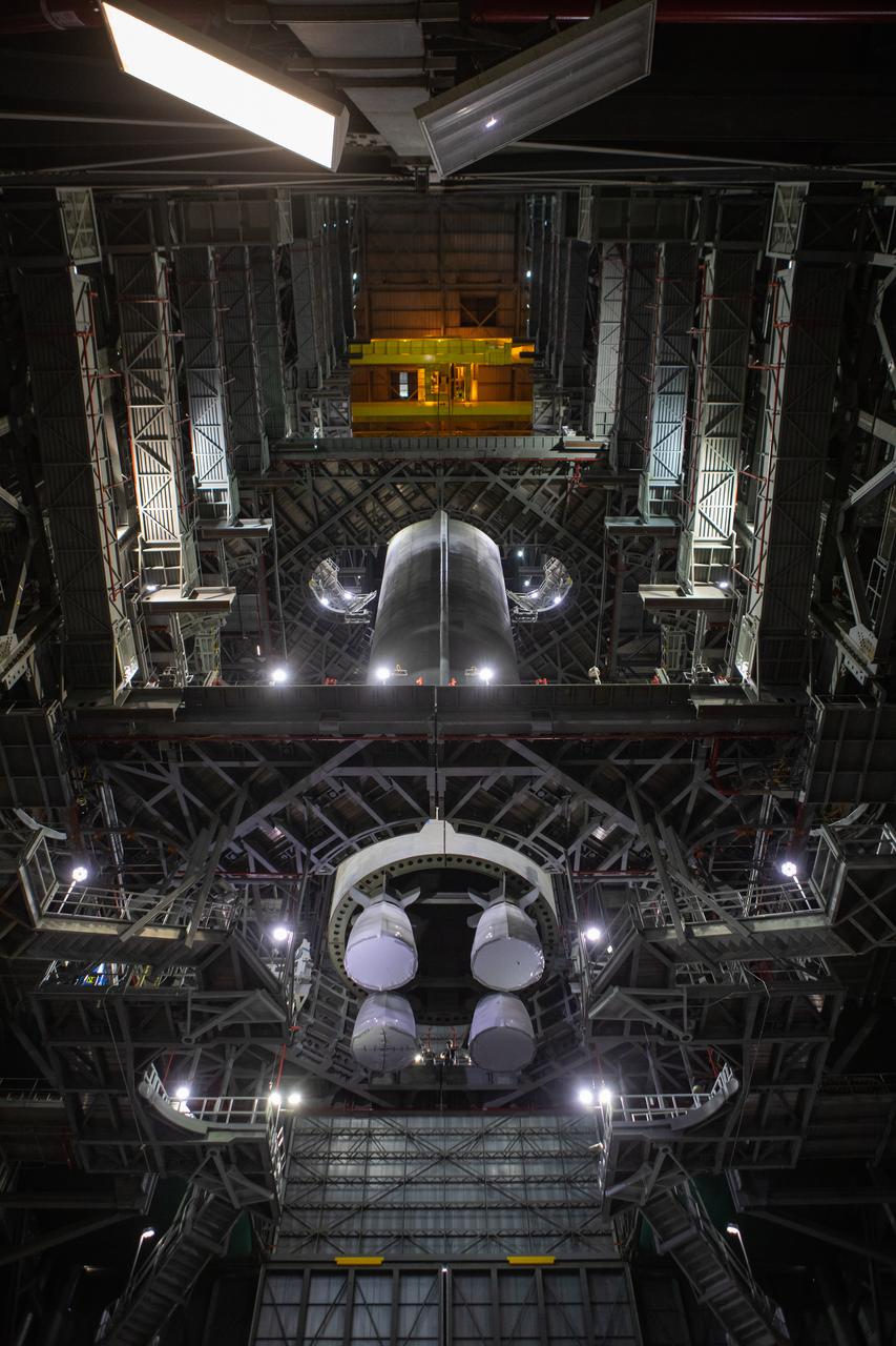 In this view looking up inside the Vehicle Assembly Building at NASA’s Kennedy Space Center in Florida, a crane lowers the Space Launch System (SLS) Core Stage pathfinder into High Bay 3 on Oct. 16, 2019. The 212-foot-long core stage pathfinder arrived on NASA's Pegasus Barge at Kennedy’s Launch Complex 39 turn basin wharf on Sept. 27, 2019. The Pegasus Barge made its first delivery to Kennedy in support of the agency's Artemis missions. The pathfinder is being used by Exploration Ground Systems and its contractor, Jacobs, to practice offloading, moving and stacking maneuvers, using important ground support equipment to train employees and certify all the equipment works properly. The pathfinder will stay at Kennedy through at least the month of October before trekking back to NASA's Michoud Assembly Facility in Louisiana.