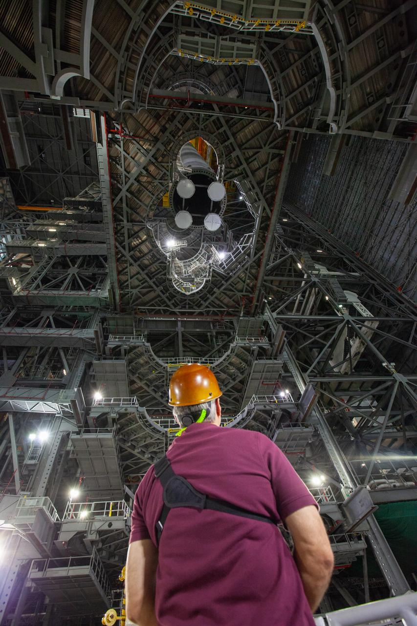 Inside the Vehicle Assembly Building at NASA’s Kennedy Space Center in Florida, a worker watches as a crane lowers the Space Launch System (SLS) Core Stage pathfinder into High Bay 3 on Oct. 16, 2019. The 212-foot-long core stage pathfinder arrived on NASA's Pegasus Barge at Kennedy’s Launch Complex 39 turn basin wharf on Sept. 27, 2019. The Pegasus Barge made its first delivery to Kennedy in support of the agency's Artemis missions. The pathfinder is being used by Exploration Ground Systems and its contractor, Jacobs, to practice offloading, moving and stacking maneuvers, using important ground support equipment to train employees and certify all the equipment works properly. The pathfinder will stay at Kennedy through at least the month of October before trekking back to NASA's Michoud Assembly Facility in Louisiana.