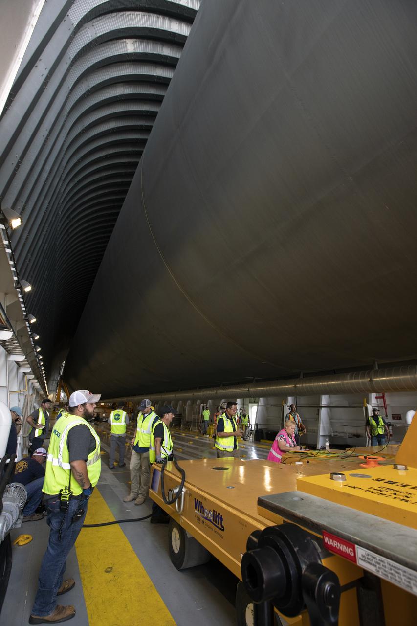 Inside the Pegasus barge at the Launch Complex 39 turn basin wharf, NASA and Jacobs workers assist as the 212-foot-long Space Launch System (SLS) rocket core stage pathfinder is moved inside the barge on Oct. 28, 2019 at NASA’s Kennedy Space Center in Florida. The core stage pathfinder is a full-scale mock-up of the rocket's core stage. It was used by the Exploration Ground Systems Program and their contractor, Jacobs, to practice offloading, moving and stacking maneuvers inside the Vehicle Assembly Building, using important ground support equipment to train employees and certify all the equipment works properly. The pathfinder was at Kennedy for about a month. It will make the trek back to NASA's Michoud Assembly Facility in Louisiana.