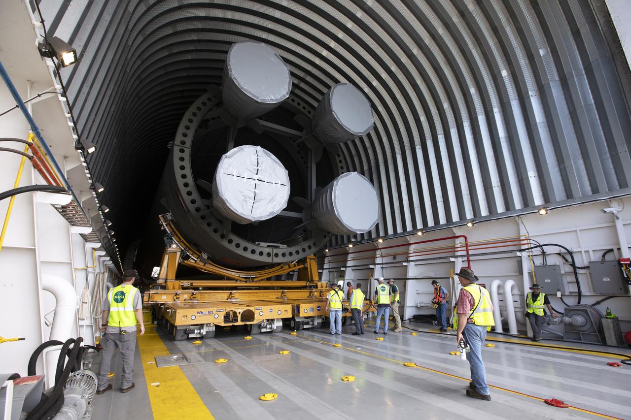 Inside the Pegasus barge at the Launch Complex 39 turn basin wharf, NASA and Jacobs workers assist as the 212-foot-long Space Launch System (SLS) rocket core stage pathfinder is moved inside the barge on Oct. 28, 2019 at NASA’s Kennedy Space Center in Florida. The core stage pathfinder is a full-scale mock-up of the rocket's core stage. It was used by the Exploration Ground Systems Program and their contractor, Jacobs, to practice offloading, moving and stacking maneuvers inside the Vehicle Assembly Building, using important ground support equipment to train employees and certify all the equipment works properly. The pathfinder was at Kennedy for about a month. It will make the trek back to NASA's Michoud Assembly Facility in Louisiana.