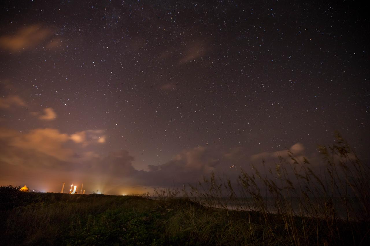 Lights from Launch Complexes 39A and B, left, glow against the night sky in this view from the Atlantic shoreline at NASA’s Kennedy Space Center in Florida on Oct. 31, 2019.