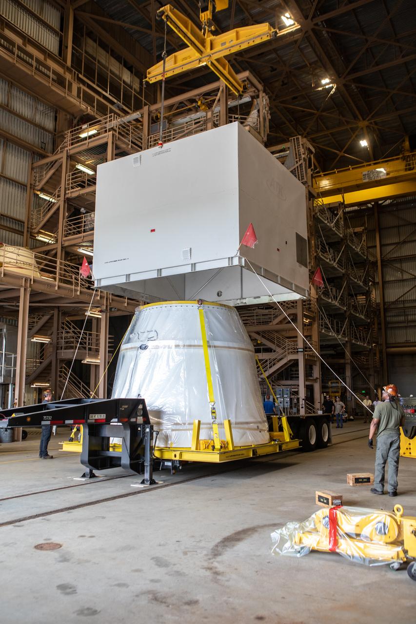 Workers assist as a crane is used to lift up the shipping container cover from the first Northrop Grumman aft exit cone to arrive for the Space Launch System’s solid rocket boosters inside the Rotation, Processing and Surge Facility at NASA’s Kennedy Space Center in Florida on Nov. 4, 2019. The aft exit cone was shipped from Promontory, Utah. It will be checked out and prepared for the Artemis I uncrewed test flight. The aft exit cones sit at the bottommost part of the twin boosters. They are attached to the aft skirts, which contain the booster separation motors. The exit cones help to protect the aft skirts during launch.