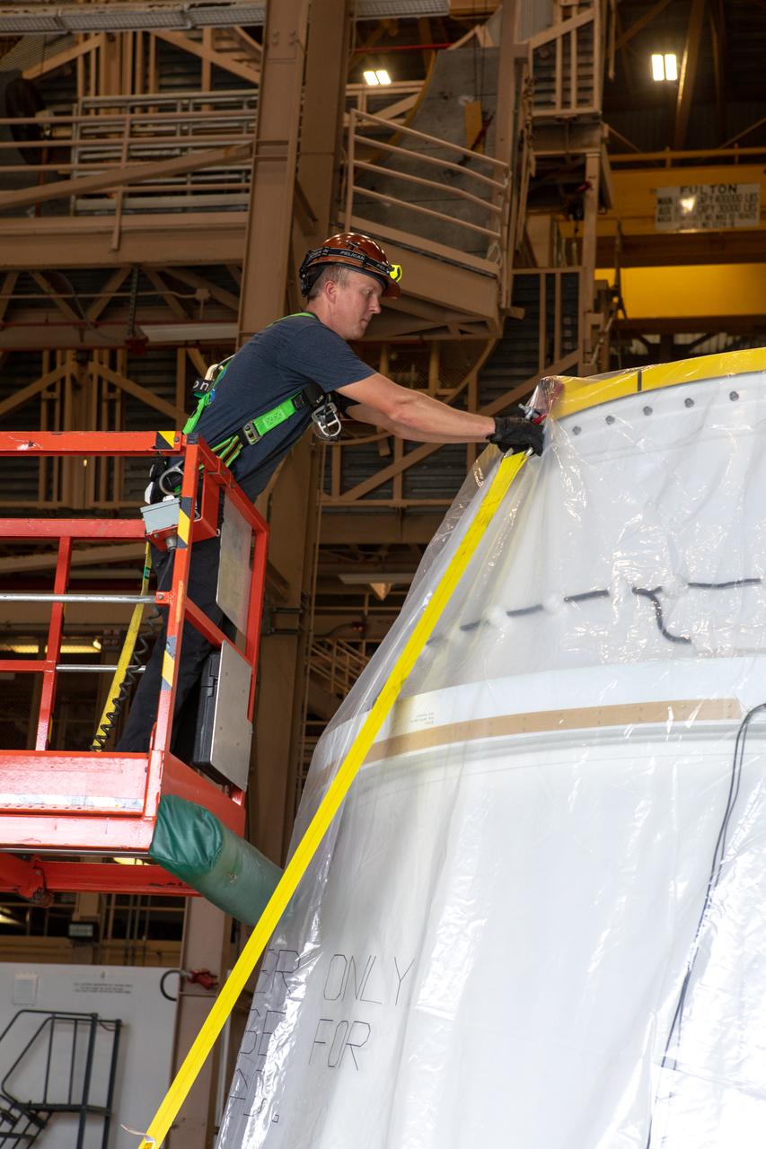 A worker removes one of the securing straps from the first Northrop Grumman aft exit cone to arrive for the Space Launch System’s solid rocket boosters inside the Rotation, Processing and Surge Facility at NASA’s Kennedy Space Center in Florida on Nov. 4, 2019. The aft exit cone was shipped from Promontory, Utah. It will be checked out and prepared for the Artemis I uncrewed test flight. The aft exit cones sit at the bottommost part of the twin boosters. They are attached to the aft skirts, which contain the booster separation motors. The exit cones help to protect the aft skirts during launch.