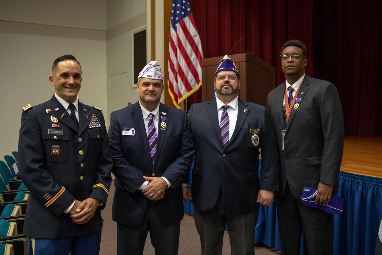 From left, NASA Public Affairs Officer Dustin Cammack, Military Order of the Purple Heart National Adjutant Ernie Rivera, Military Order of the Purple Heart Department of Florida Commander Christopher Vedvick and NASA Public Affairs Officer Derrick Matthews are photographed inside Kennedy Space Center’s Training Auditorium during a Veterans Day observance ceremony on Nov. 7, 2019. During the event, Kennedy was named a Purple Heart Entity by the Military Order of the Purple Heart, becoming the first NASA center to receive this designation for support and services provided to veterans through the Florida spaceport’s Veterans employee resource group. Attendees included Kennedy employees and more than 20 Purple Heart recipients. Following the award presentation, Vedvick, a combat wounded veteran, spoke about his experience serving in the United States Army before retiring, his involvement in the Military Order of the Purple Heart and the purpose of the organization.