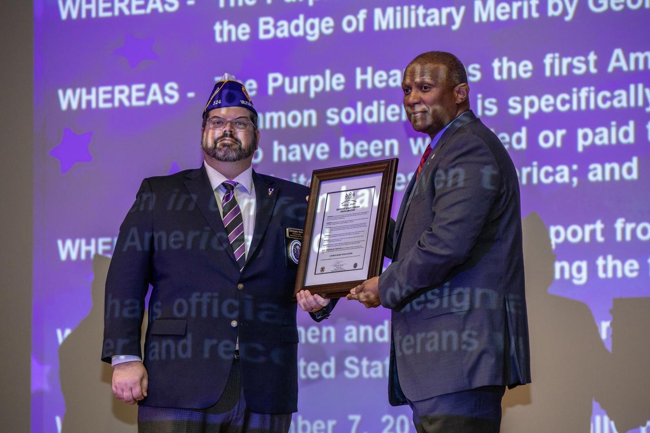 Christopher Vedvick, left, a combat wounded veteran and Military Order of the Purple Heart department of Florida commander, presents Kennedy Space Center’s Associate Director, Technical, Kelvin Manning with a proclamation designating Kennedy a Purple Heart Entity during a Veterans Day observance event on Nov. 7, 2019, in the Training Auditorium. Kennedy is the first NASA center to receive this designation for support and services provided to veterans through the Florida spaceport’s Veterans employee resource group. Attendees included Kennedy employees and more than 20 Purple Heart recipients. Following this recognition, Vedvick, spoke about his experience serving in the United States Army before retiring, his involvement in the Military Order of the Purple Heart and the purpose of the organization.
