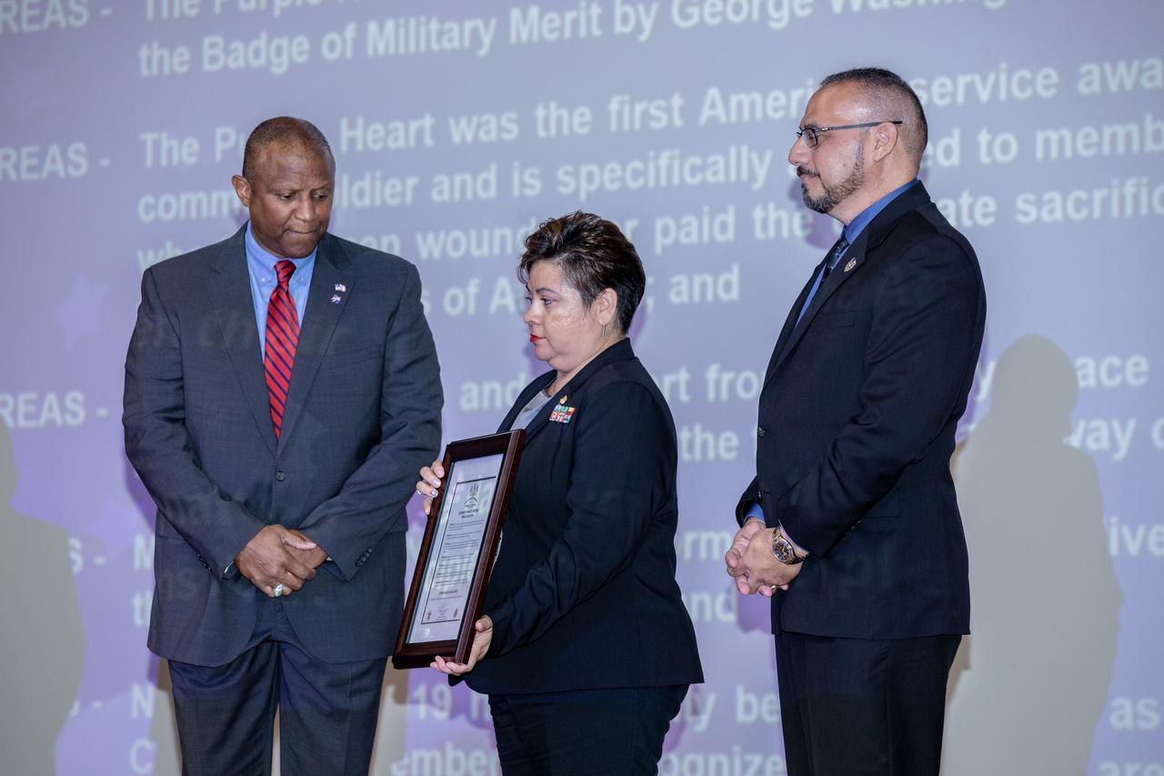 From left, Kennedy Space Center Associate Director, Technical, Kelvin Manning, Kennedy’s Veterans employee resource group chair Ana Contreras and executive champion Edwin Martinez are photographed with the proclamation designating Kennedy a Purple Heart Entity on Nov. 7, 2019. The proclamation was presented by the Military Order of the Purple Heart during a Veterans Day observance event held in the center’s Training Auditorium. Kennedy is the first NASA center to receive this designation for support and services provided to veterans through the Florida spaceport’s Veterans employee resource group. Attendees included Kennedy employees and more than 20 Purple Heart recipients. Following this, Christopher Vedvick, a combat wounded veteran and Military Order of the Purple Heart department of Florida commander, spoke about his experience serving in the United States Army before retiring, his involvement in the Military Order of the Purple Heart and the purpose of the organization.