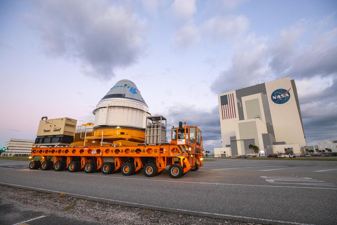 Boeing’s CST-100 Starliner spacecraft passes by the Vehicle Assembly Building at NASA’s Kennedy Space Center in Florida on Nov. 21, 2019, making its way to the Space Launch Complex 41 Vertical Integration Facility at Cape Canaveral Air Force Station. At the pad, Starliner will be secured atop a United Launch Alliance Atlas V rocket in preparation for Boeing’s uncrewed Orbital Flight Test to the International Space Station for NASA’s Commercial Crew Program.