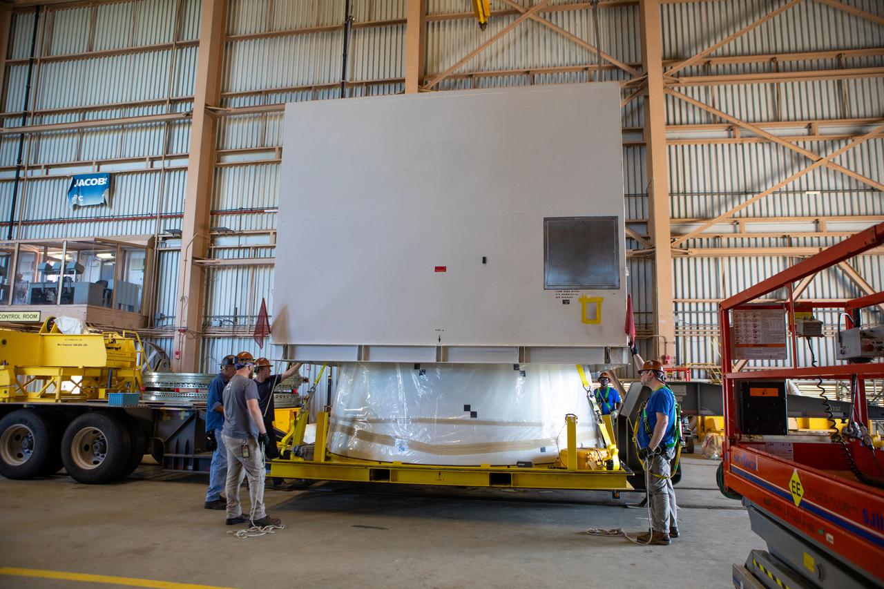 Workers assist with removal of the shipping container cover from the second Northrop Grumman-manufactured aft exit cone to arrive for the Space Launch System’s solid rocket boosters inside the Rotation, Processing and Surge Facility at NASA’s Kennedy Space Center in Florida on Dec. 9, 2019. The right aft exit cone was shipped from Promontory, Utah. It will be checked out and prepared for the Artemis I uncrewed test flight. The aft exit cones sit at the bottommost part of the twin boosters. The cones help provide added thrust for the boosters, while protecting the aft skirts from the thermal environment during launch.