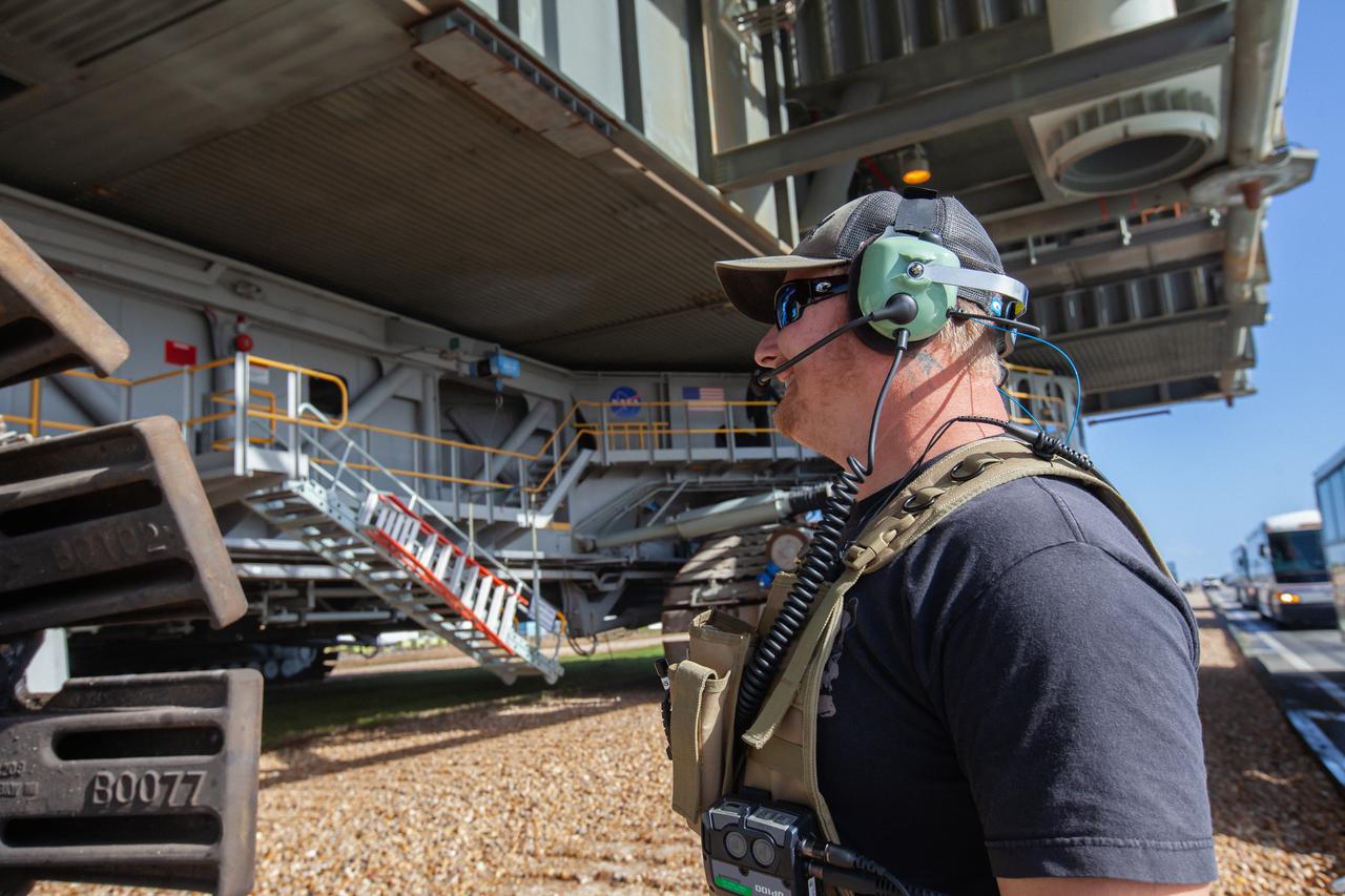 A Kennedy Space Center employee monitors the roll of the mobile launcher, carried atop the crawler-transporter 2, as it returns to the Vehicle Assembly Building on Dec. 20, 2019, after spending months at Launch Pad 39B undergoing final validation and verification testing at NASA’s Kennedy Space Center in Florida. Standing 380 feet tall, the mobile launcher – which will be used to assemble, process and launch the Space Launch System and Orion spacecraft – will remain inside the VAB until it is ready to return to the pad with the rocket and spacecraft on top for the “wet dress rehearsal” ahead of the Artemis I launch. 