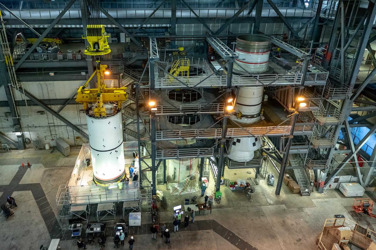 In High Bay 4 of the Vehicle Assembly Building at NASA’s Kennedy Space Center in Florida, pathfinders, or full-scale replicas of Space Launch System (SLS) solid rocket booster segments, are being stacked during a training exercise on Jan. 8, 2020. A team of engineers with Exploration Ground Systems and crane operators and technicians with contractor Jacobs are practicing lifting, moving and stacking maneuvers, using important ground support equipment to train employees and certify all the equipment works properly. The booster pathfinders are inert, full-scale replicas of the actual booster hardware that will be attached to the SLS rocket for Artemis missions. The five-segment, 17-story-tall twin boosters will provide 3.6 million pounds of thrust each at liftoff to help launch Orion on Artemis I, its first uncrewed mission beyond the Moon.