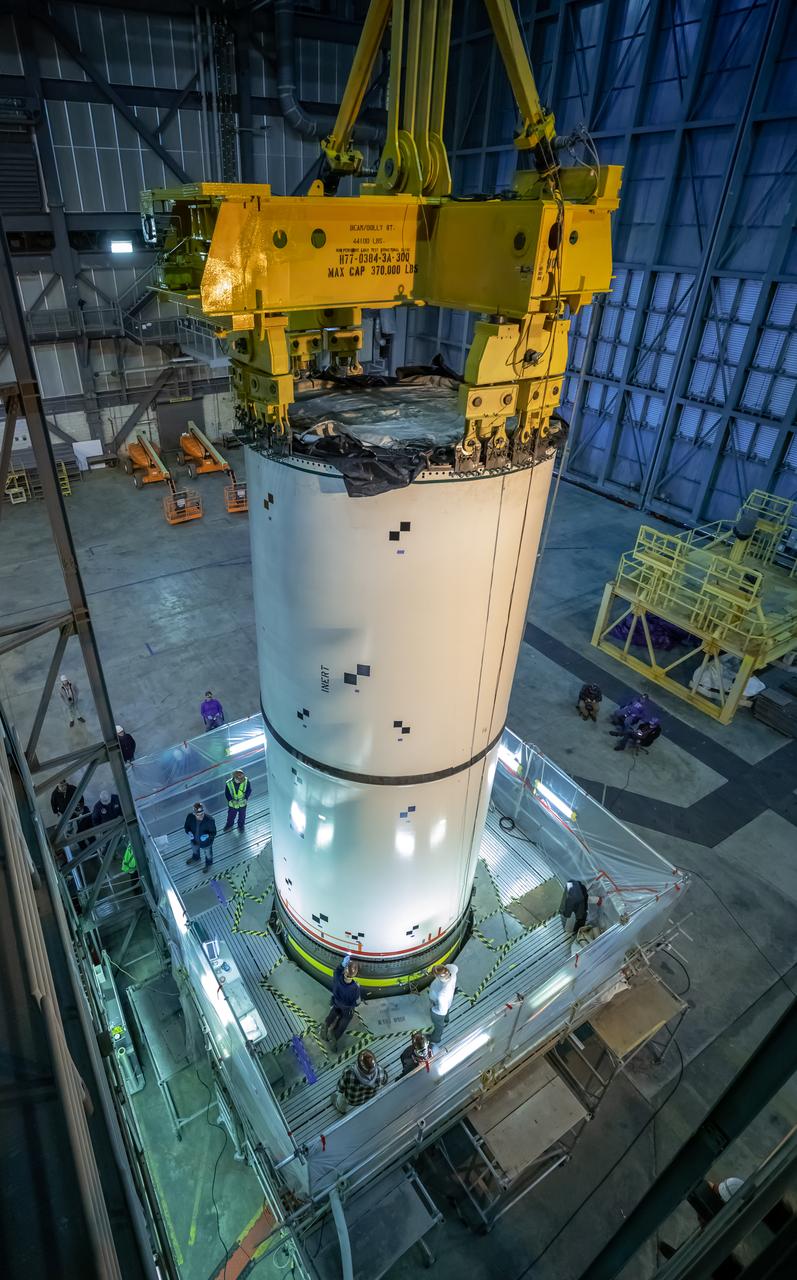 In High Bay 4 of the Vehicle Assembly Building at NASA’s Kennedy Space Center in Florida, a crane lowers Space Launch System (SLS) solid rocket booster pathfinder segments onto a platform during a training exercise on Jan. 8, 2020. A team of engineers with Exploration Ground Systems and crane operators and technicians with contractor Jacobs are practicing lifting, moving and stacking maneuvers, using important ground support equipment to train employees and certify all the equipment works properly. The booster pathfinders are inert, full-scale replicas of the actual booster hardware that will be attached to the SLS rocket for Artemis missions. The five-segment, 17-story-tall twin boosters will provide 3.6 million pounds of thrust each at liftoff to help launch Orion on Artemis I, its first uncrewed mission beyond the Moon.