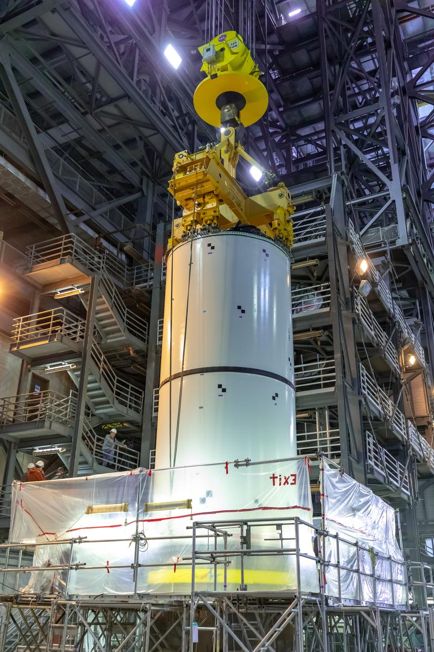 In High Bay 4 of the Vehicle Assembly Building at NASA’s Kennedy Space Center in Florida, a crane lowers Space Launch System (SLS) solid rocket booster pathfinder segments onto a platform during a training exercise on Jan. 8, 2020. A team of engineers with Exploration Ground Systems and crane operators and technicians with contractor Jacobs are practicing lifting, moving and stacking maneuvers, using important ground support equipment to train employees and certify all the equipment works properly. The booster pathfinders are inert, full-scale replicas of the actual booster hardware that will be attached to the SLS rocket for Artemis missions. The five-segment, 17-story-tall twin boosters will provide 3.6 million pounds of thrust each at liftoff to help launch Orion on Artemis I, its first uncrewed mission beyond the Moon.
