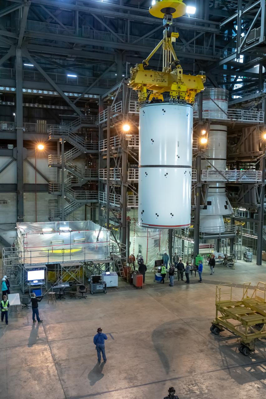 In High Bay 4 of the Vehicle Assembly Building at NASA’s Kennedy Space Center in Florida, a crane moves Space Launch System (SLS) solid rocket booster pathfinder segments toward a platform during a training exercise on Jan. 8, 2020. A team of engineers with Exploration Ground Systems and crane operators and technicians with contractor Jacobs are practicing lifting, moving and stacking maneuvers, using important ground support equipment to train employees and certify all the equipment works properly. The booster pathfinders are inert, full-scale replicas of the actual booster hardware that will be attached to the SLS rocket for Artemis missions. The five-segment, 17-story-tall twin boosters will provide 3.6 million pounds of thrust each at liftoff to help launch Orion on Artemis I, its first uncrewed mission beyond the Moon.