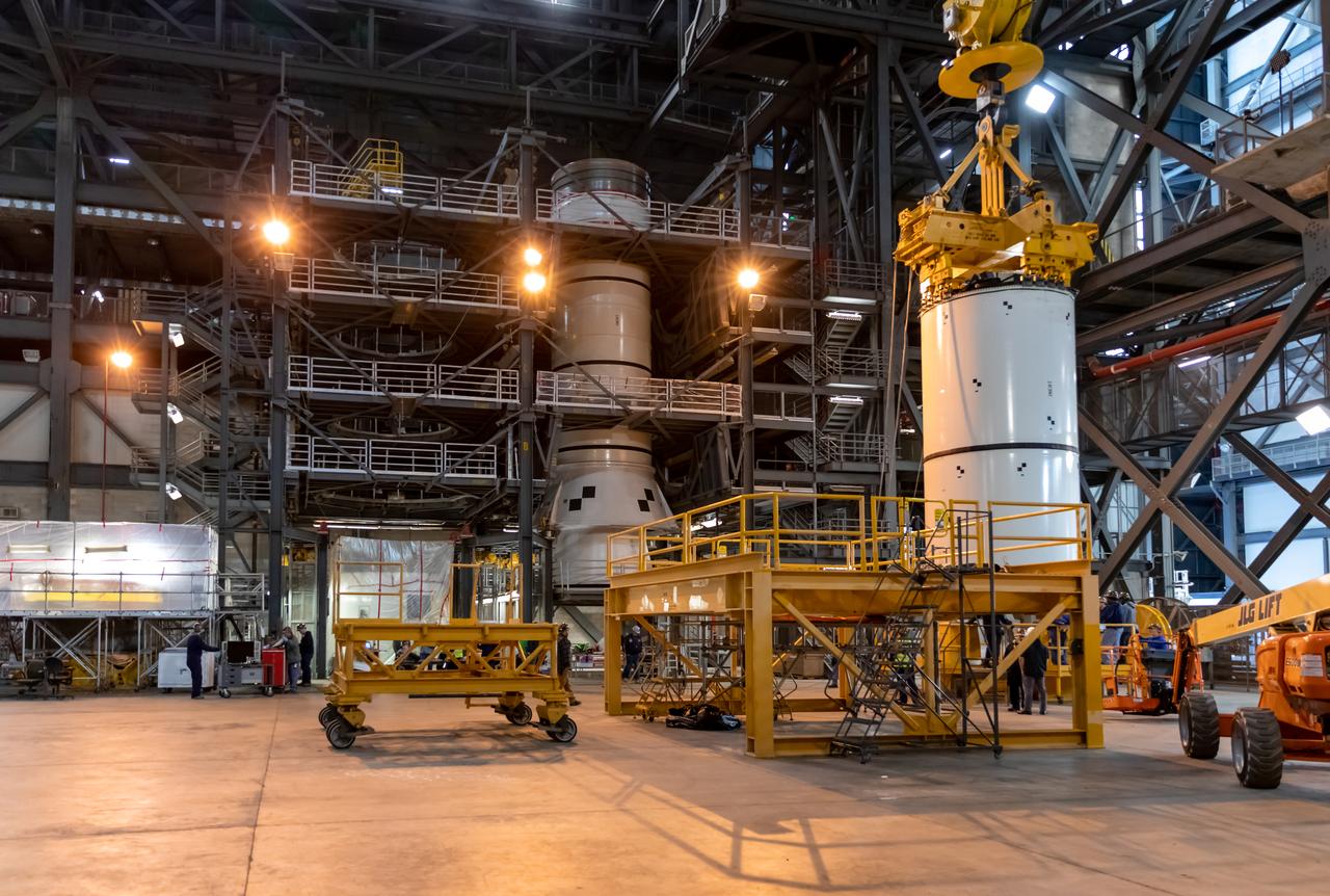 In High Bay 4 of the Vehicle Assembly Building at NASA’s Kennedy Space Center in Florida, a crane is used to lift Space Launch System (SLS) solid rocket booster pathfinder segments and move them to be added atop other booster pathfinder segments during a training exercise on Jan. 8, 2020. A team of engineers with Exploration Ground Systems and crane operators and technicians with contractor Jacobs are practicing lifting, moving and stacking maneuvers, using important ground support equipment to train employees and certify all the equipment works properly. The booster pathfinders are inert, full-scale replicas of the actual booster hardware that will be attached to the SLS rocket for Artemis missions. The five-segment, 17-story-tall twin boosters will provide 3.6 million pounds of thrust each at liftoff to help launch Orion on Artemis I, its first uncrewed mission beyond the Moon.