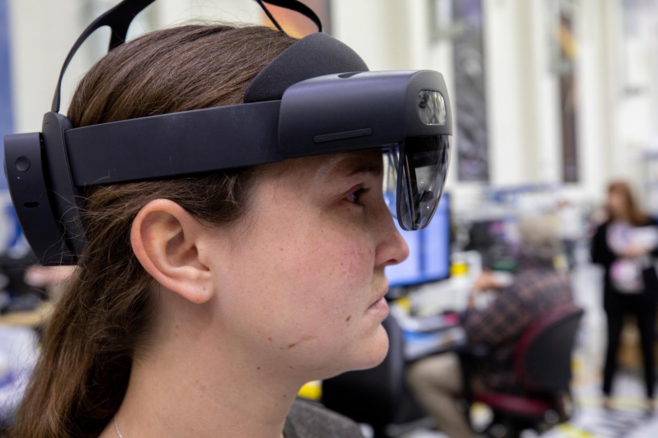 Mary Lakaszcyck, a technician with ASRC Federal Data Solutions, wears a pair of augmented reality (AR) goggles inside the high bay of the Neil Armstrong Operations and Checkout Building at NASA’s Kennedy Space Center in Florida on Jan. 16, 2020. Orion manufacturer Lockheed Martin provided the goggles to technicians to help place tapes where components will be installed on the Orion crew module adapter for NASA’s Artemis II mission, the first crewed mission aboard the spacecraft. Using the AR goggles saves significant labor and time to complete tasks. Manufactured by Microsoft, the goggles, called HoloLens2, are the second version used by Lockheed.