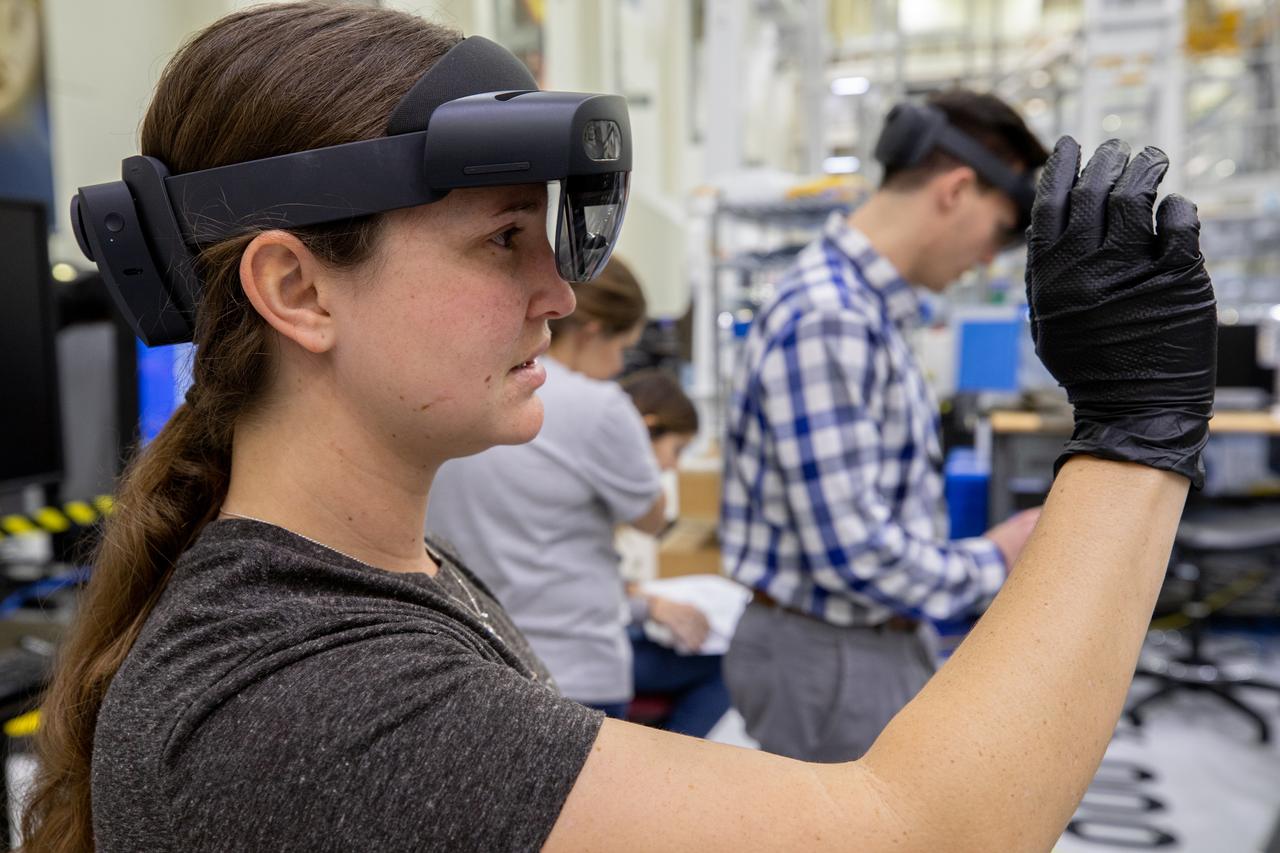 Mary Lakaszcyck, a technician with ASRC Federal Data Solutions, demonstrates a pair of augmented reality (AR) goggles inside the high bay of the Neil Armstrong Operations and Checkout Building at NASA’s Kennedy Space Center in Florida on Jan. 16, 2020. Orion manufacturer Lockheed Martin provided the goggles to technicians to help place tapes where components will be installed on the Orion crew module adapter for NASA’s Artemis II mission, the first crewed mission aboard the spacecraft. Using the AR goggles saves significant labor and time to complete tasks. Manufactured by Microsoft, the goggles, called HoloLens2, are the second version used by Lockheed.