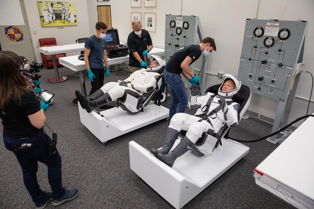 NASA astronauts Doug Hurley, foreground, and Bob Behnken don SpaceX spacesuits in the Astronaut Crew Quarters at Kennedy Space Center in Florida on Jan. 17, 2020, during a dress rehearsal ahead of the company’s uncrewed In-Flight Abort Test. A SpaceX Falcon 9 rocket and Crew Dragon spacecraft will lift off from Launch Complex 39A on the flight test, which will demonstrate the spacecraft’s escape capabilities in preparation for crewed flights to the International Space Station as part of the agency’s Commercial Crew Program. Hurley and Behnken are slated to fly on the company’s first crewed mission, Demo-2.