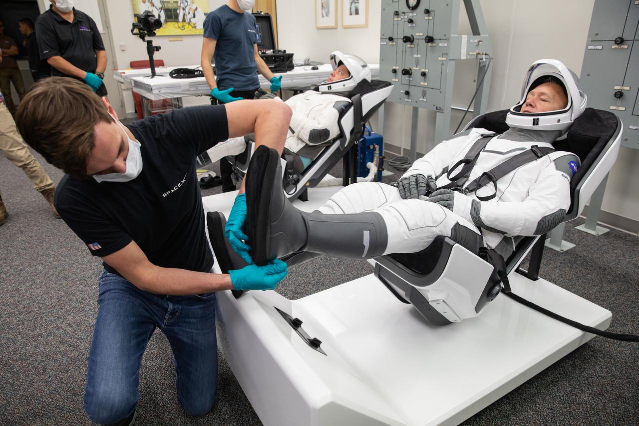 NASA astronauts Doug Hurley, foreground, and Bob Behnken don SpaceX spacesuits in the Astronaut Crew Quarters at Kennedy Space Center in Florida on Jan. 17, 2020, during a dress rehearsal ahead of the company’s uncrewed In-Flight Abort Test. A SpaceX Falcon 9 rocket and Crew Dragon spacecraft will lift off from Launch Complex 39A on the flight test, which will demonstrate the spacecraft’s escape capabilities in preparation for crewed flights to the International Space Station as part of the agency’s Commercial Crew Program. Hurley and Behnken are slated to fly on the company’s first crewed mission, Demo-2.