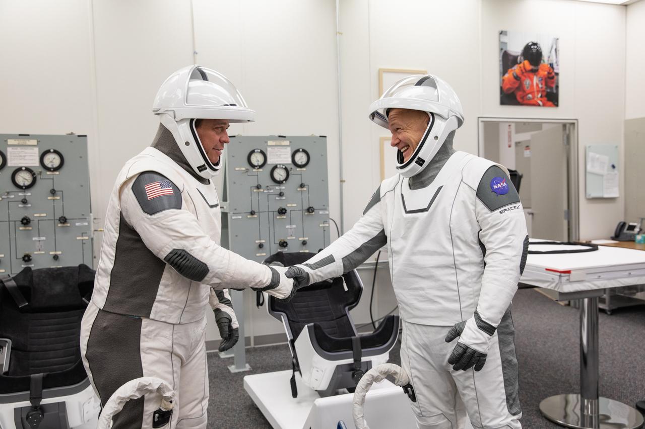 NASA astronauts Bob Behnken, left, and Doug Hurley shake hands after suiting up in SpaceX spacesuits in the Astronaut Crew Quarters at Kennedy Space Center in Florida on Jan. 17, 2020, during a dress rehearsal ahead of the company’s uncrewed In-Flight Abort Test. A SpaceX Falcon 9 rocket and Crew Dragon spacecraft will lift off from Launch Complex 39A on the flight test, which will demonstrate the spacecraft’s escape capabilities in preparation for crewed flights to the International Space Station as part of the agency’s Commercial Crew Program. Behnken and Hurley are slated to fly on the company’s first crewed mission, Demo-2.