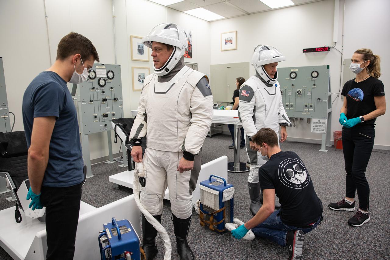 NASA astronauts Bob Behnken, foreground, and Doug Hurley don SpaceX spacesuits in the Astronaut Crew Quarters at Kennedy Space Center in Florida on Jan. 17, 2020, during a dress rehearsal ahead of the company’s uncrewed In-Flight Abort Test. A SpaceX Falcon 9 rocket and Crew Dragon spacecraft will lift off from Launch Complex 39A on the flight test, which will demonstrate the spacecraft’s escape capabilities in preparation for crewed flights to the International Space Station as part of the agency’s Commercial Crew Program. Behnken and Hurley are slated to fly on the company’s first crewed mission, Demo-2.