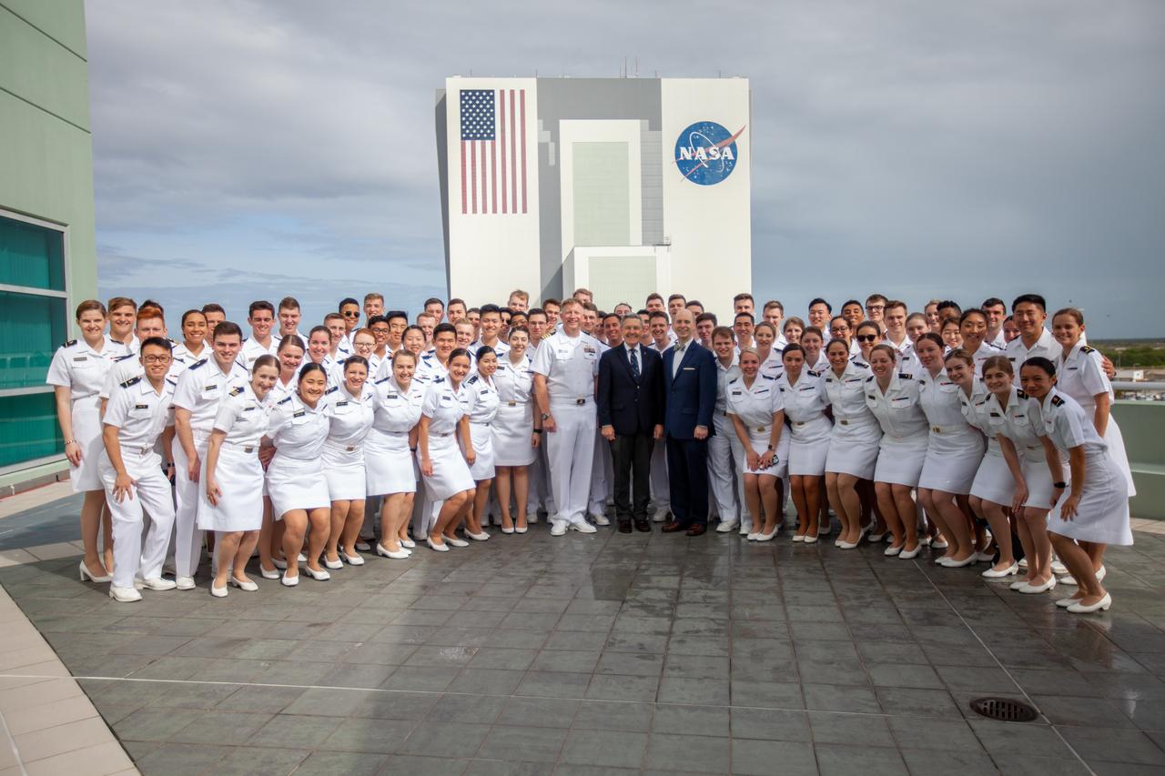 At center, from left to right, Captain Ben Shupp, commanding officer, Naval Ordnance Test Unit; Bob Cabana, Kennedy Space Center director; and Dr. Aaron Smith, director and chairman, Musical Activities Department, United States Naval Academy; pose with the U.S. Naval Academy Glee Club with the Florida spaceport’s Vehicle Assembly Building in the background on March 10, 2020. The highly acclaimed Glee Club, which performed for Kennedy employees, has achieved prominence as one of America’s premier choral ensembles.
