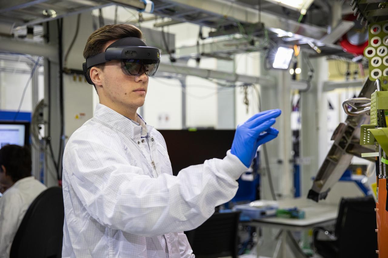 Michael Maxwell, with Lockheed Martin’s augmented reality team, wears a pair of augmented reality (AR) goggles to work on the crew module for NASA’s Artemis II mission inside the high bay of the Neil Armstrong Operations and Checkout Building at the agency’s Kennedy Space Center in Florida on March 18, 2020. Orion manufacturer Lockheed Martin provided the goggles to technicians to help place tapes where components will be installed on the crew module adapter for Artemis II, the first crewed mission aboard the spacecraft. Using the AR goggles saves significant labor and time to complete tasks. Manufactured by Microsoft, the goggles, called HoloLens2, are the second version used by Lockheed.