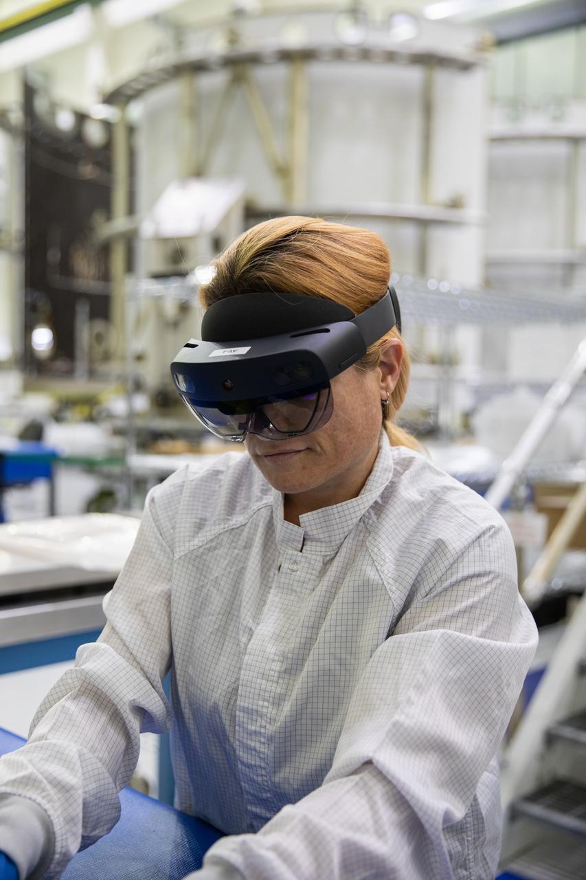Jennifer Solano, with Lockheed Martin at Kennedy Space Center in Florida, wears a pair of augmented reality (AR) goggles to work on crew module hardware for NASA’s Artemis II mission inside the high bay of the Neil Armstrong Operations and Checkout Building at Kennedy on March 18, 2020. Orion manufacturer Lockheed Martin provided the goggles to technicians to help place tapes where components will be installed on Orion for Artemis II, the first crewed mission aboard the spacecraft. Using the AR goggles saves significant labor and time to complete tasks. Manufactured by Microsoft, the goggles, called HoloLens2, are the second version used by Lockheed.