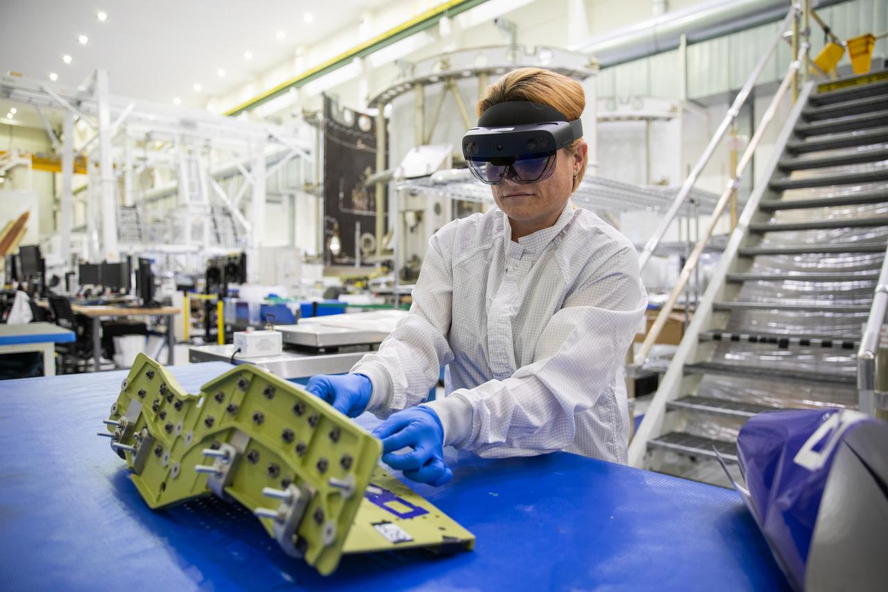 Jennifer Solano, with Lockheed Martin at Kennedy Space Center in Florida, wears a pair of augmented reality (AR) goggles to work on crew module hardware for NASA’s Artemis II mission inside the high bay of the Neil Armstrong Operations and Checkout Building at Kennedy on March 18, 2020. Orion manufacturer Lockheed Martin provided the goggles to technicians to help place tapes where components will be installed on Orion for Artemis II, the first crewed mission aboard the spacecraft. Using the AR goggles saves significant labor and time to complete tasks. Manufactured by Microsoft, the goggles, called HoloLens2, are the second version used by Lockheed.