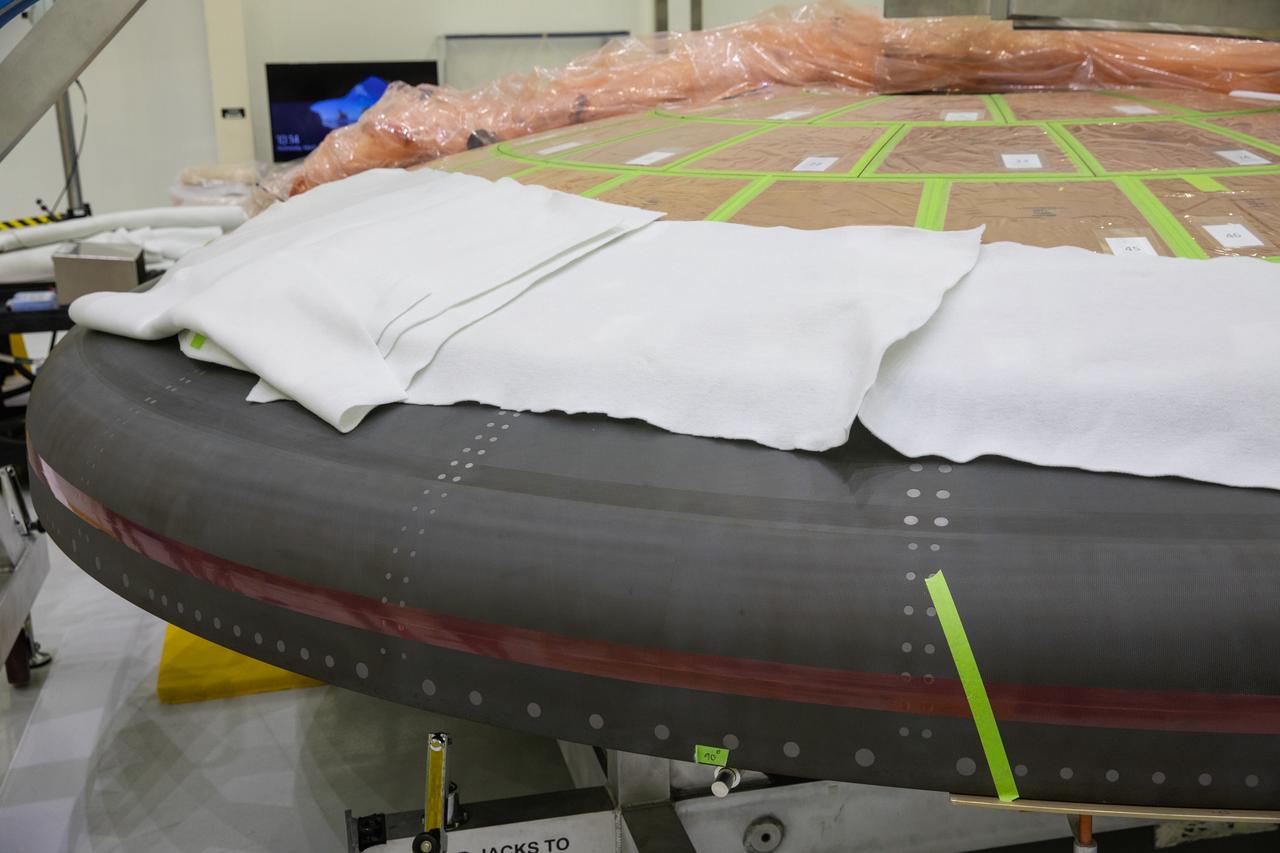 The heat shield for NASA’s Artemis II mission is in view inside the Neil Armstrong Operations and Checkout Building at the agency’s Kennedy Space Center in Florida on March 18, 2020. Using augmented reality (AR) goggles, technicians are completing the work on the heat shield. Orion manufacturer Lockheed Martin provided the goggles to technicians to help place tapes where components will be installed on the crew module, heat shield and other components for Artemis II, the first crewed mission aboard the spacecraft. Using the AR goggles saves significant labor and time to complete tasks. Manufactured by Microsoft, the goggles, called HoloLens2, are the second version used by Lockheed.