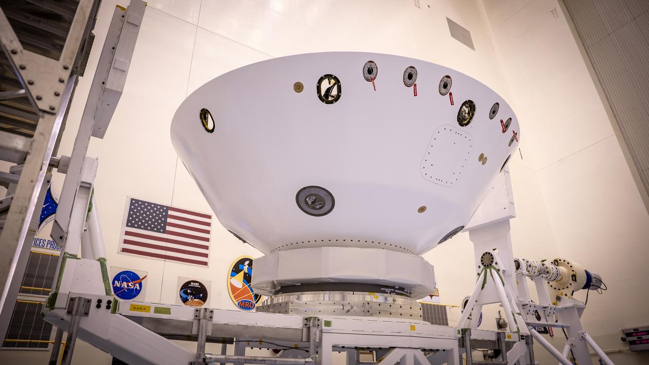 Inside the Payload Hazardous Servicing Facility at NASA’s Kennedy Space Center in Florida, the Mars Perseverance rover is rotated to prepare for the Backshell-Powered Descent Vehicle and Entry Vehicle assemblies to be attached on May 4, 2020. The cone-shaped backshell contains the parachute, and along with the mission’s heat shield, provides protection for the rover and descent stage during Martian atmospheric entry. The Mars Perseverance rover is scheduled to launch in mid-July atop a United Launch Alliance Atlas V 541 rocket from Pad 41 at nearby Cape Canaveral Air Force Station. The rover is part of NASA’s Mars Exploration Program, a long-term effort of robotic exploration of the Red Planet. The rover will search for habitable conditions in the ancient past and signs of past microbial life on Mars. The Launch Services Program at Kennedy is responsible for launch management.