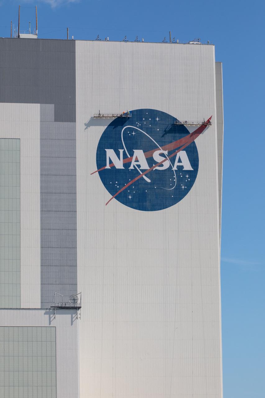 Painting of the NASA logo, also called the meatball, is underway on the 525-foot-tall Vehicle Assembly Building (VAB) at the agency’s Kennedy Space Center in Florida on May 8, 2020. HM2 and H.I.S. Painting of Titusville, Florida, are repainting the meatball and the American Flag on the iconic building. High Bay 3 inside the VAB has been upgraded with 10 new levels of work platforms that will surround and provide access for service and processing of NASA's Space Launch System (SLS) rocket and Orion spacecraft. Exploration Ground Systems is overseeing upgrades to the VAB to support the launch of the SLS and Orion for Artemis missions. Under the Artemis program, NASA will send the first woman and next man to the Moon.